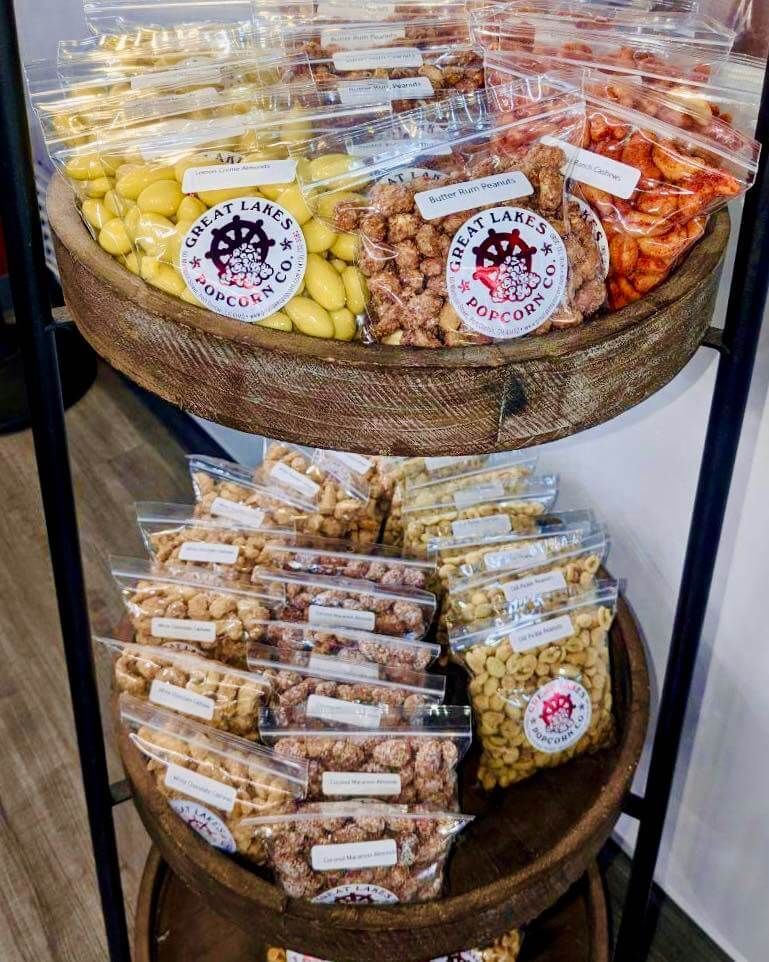 A wooden shelf filled with bags of nuts and other snacks available at Great Lakes Popcorn Co.