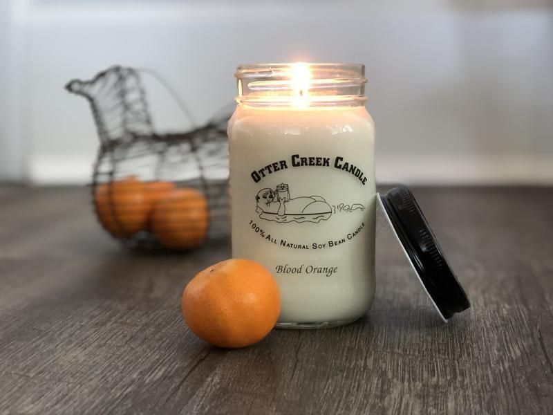 A jar of bitter creek candle next to an orange