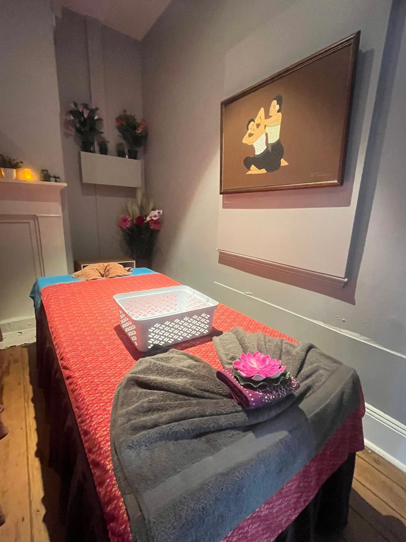 Massage Table with Red and Gray Blankets in A Softly Lit Treatment Room — Thai Massage In Bathurst, NSW