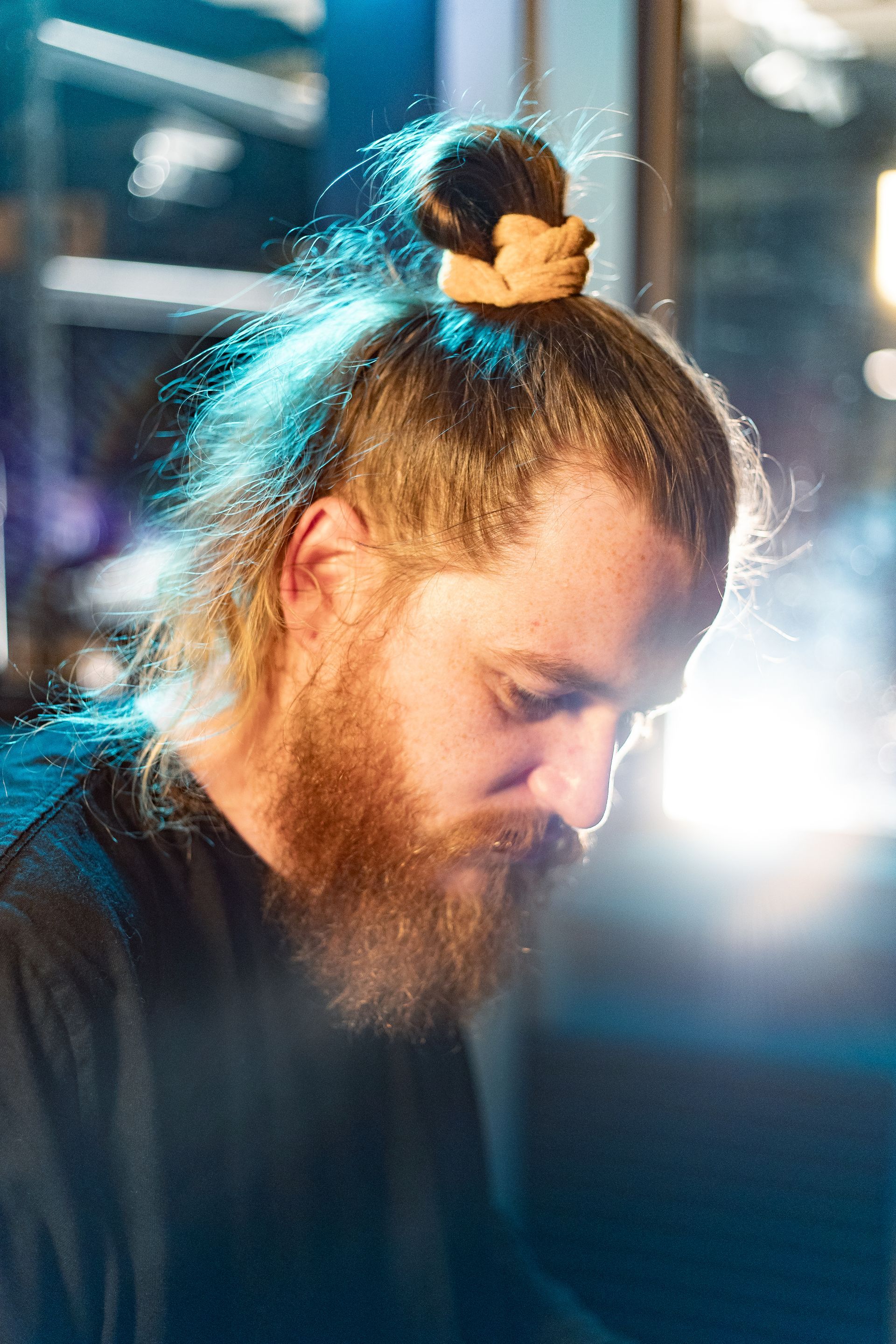 A man with a beard and long hair is wearing a bun.