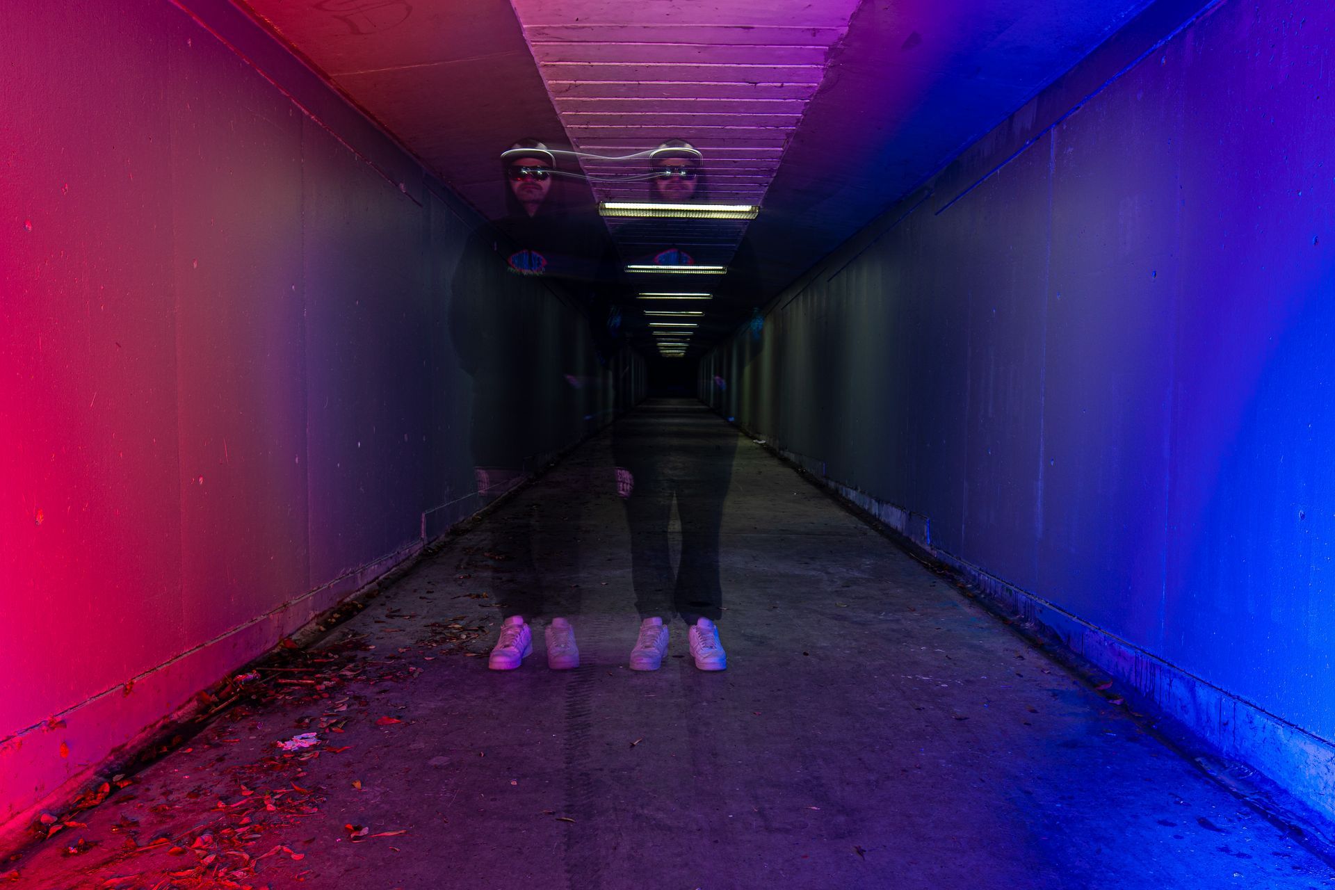 A person is standing in a tunnel with red and blue lights.