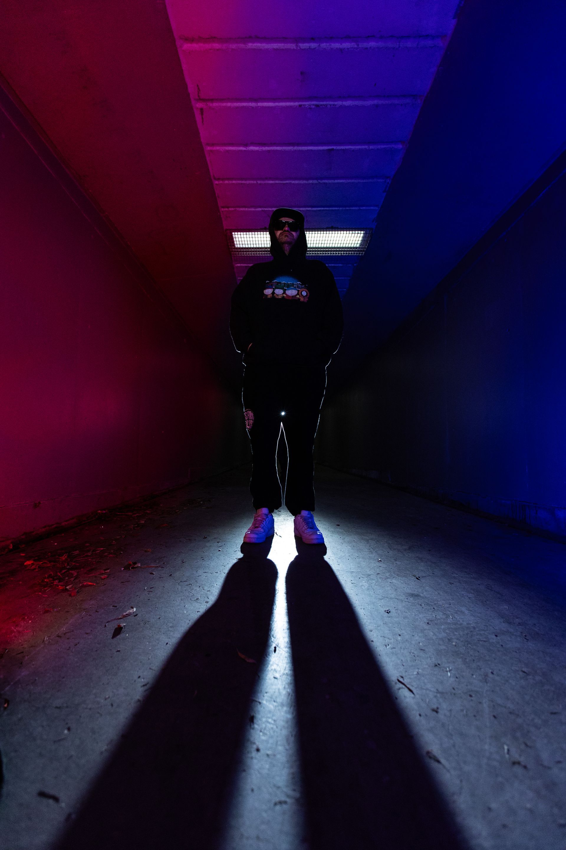 A man is standing in a dark room with a shadow on the floor.