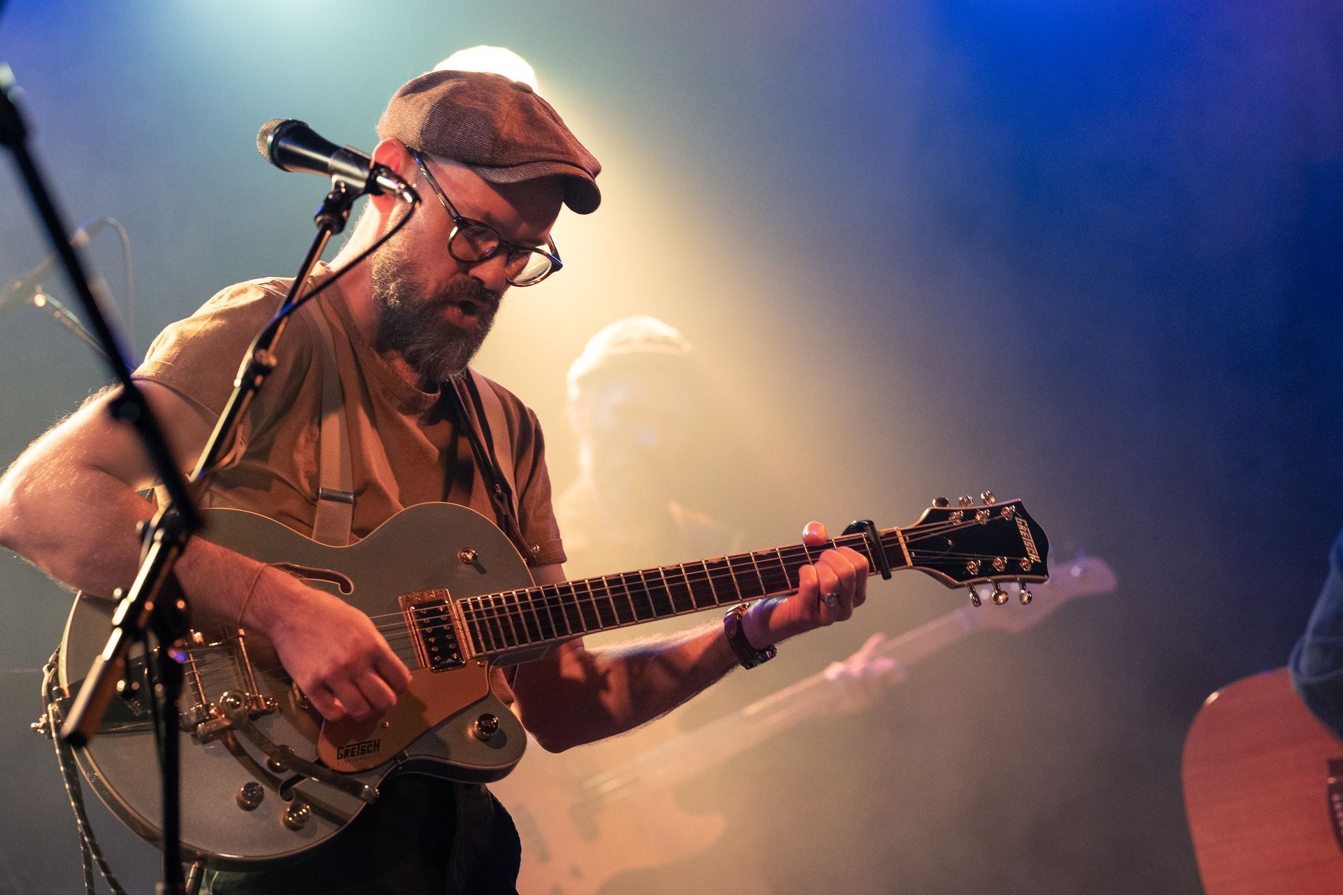 A man is playing a guitar and singing into a microphone on a stage.