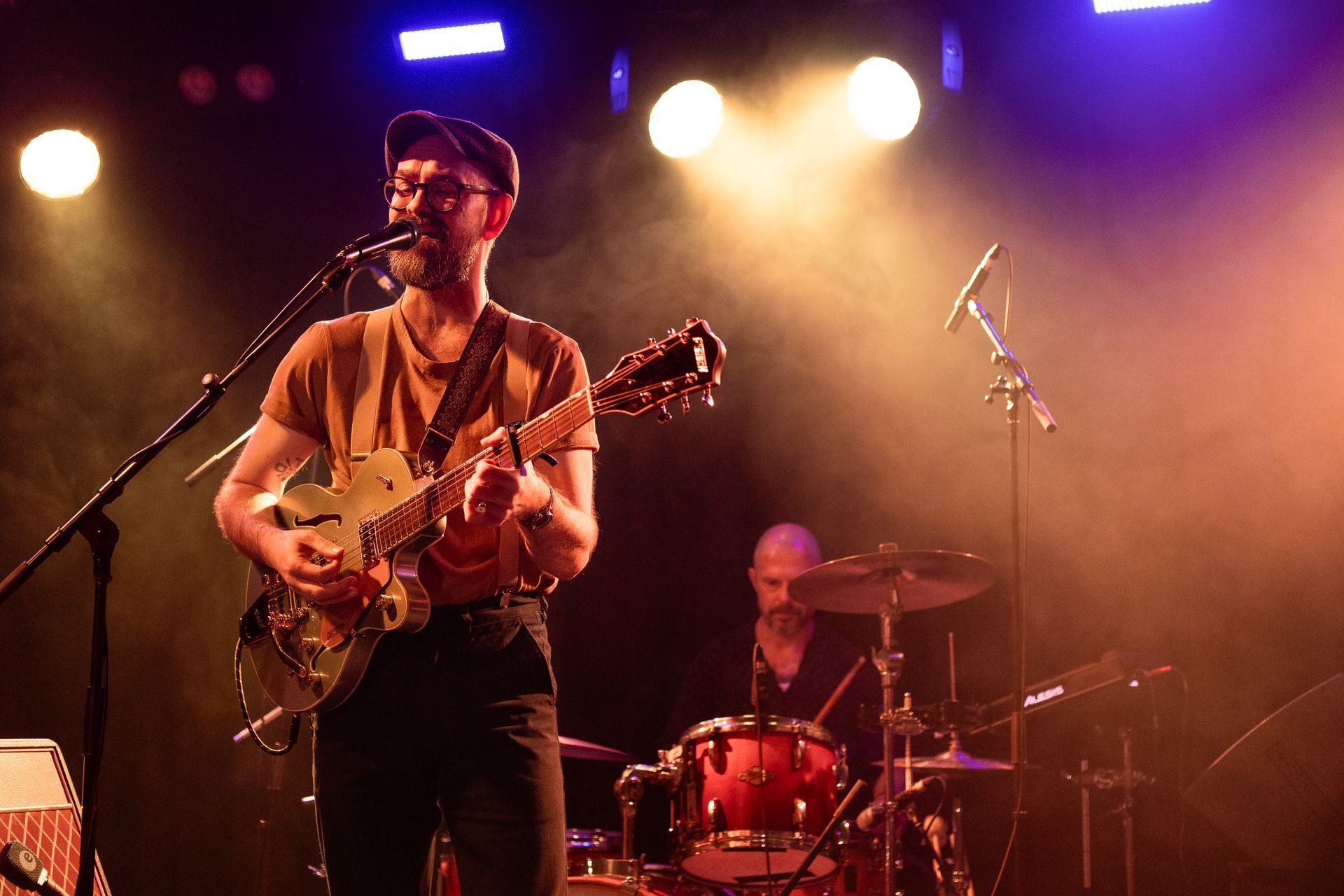 A man is playing a guitar and singing into a microphone on a stage.