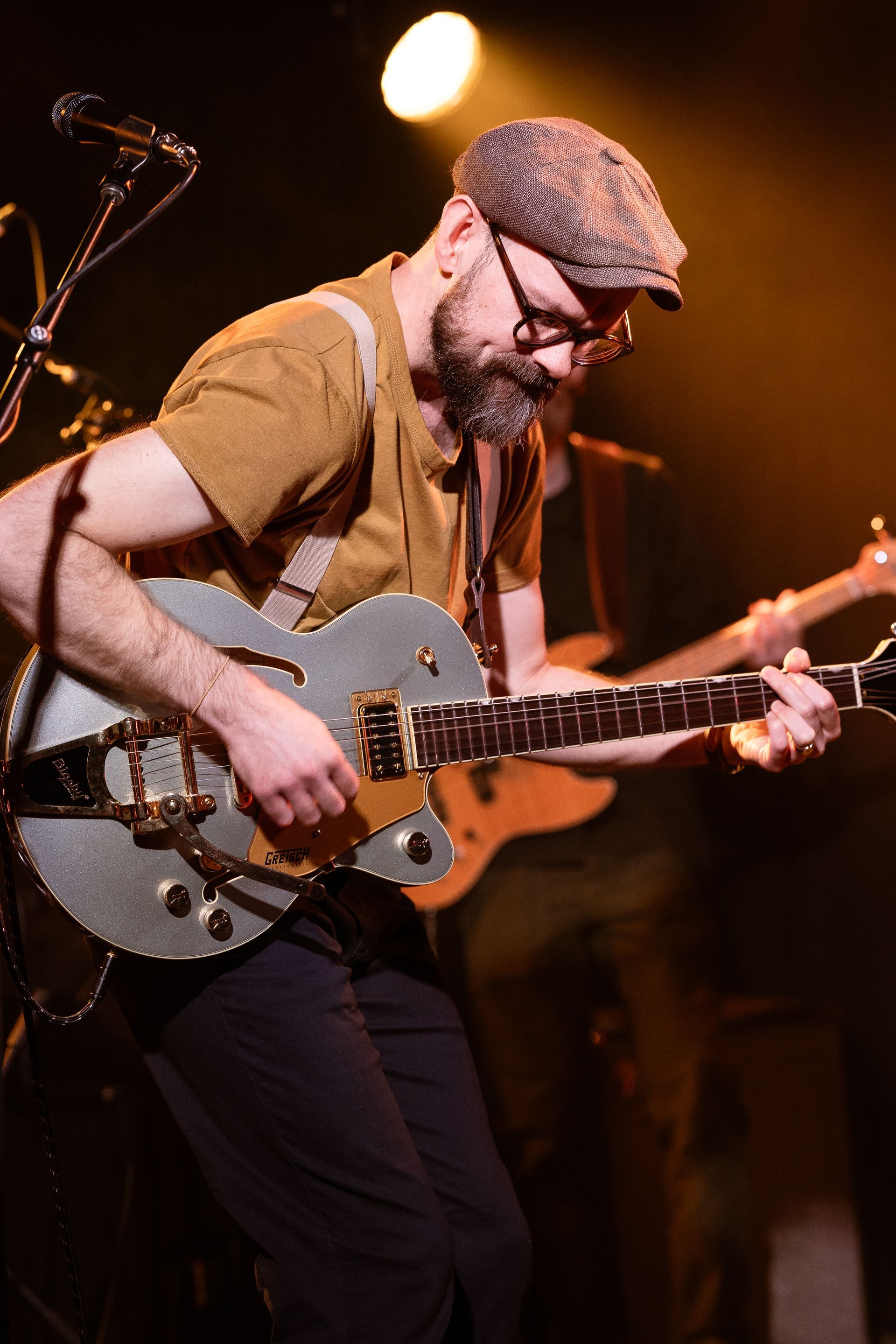 A man is playing a guitar and singing into a microphone on stage.