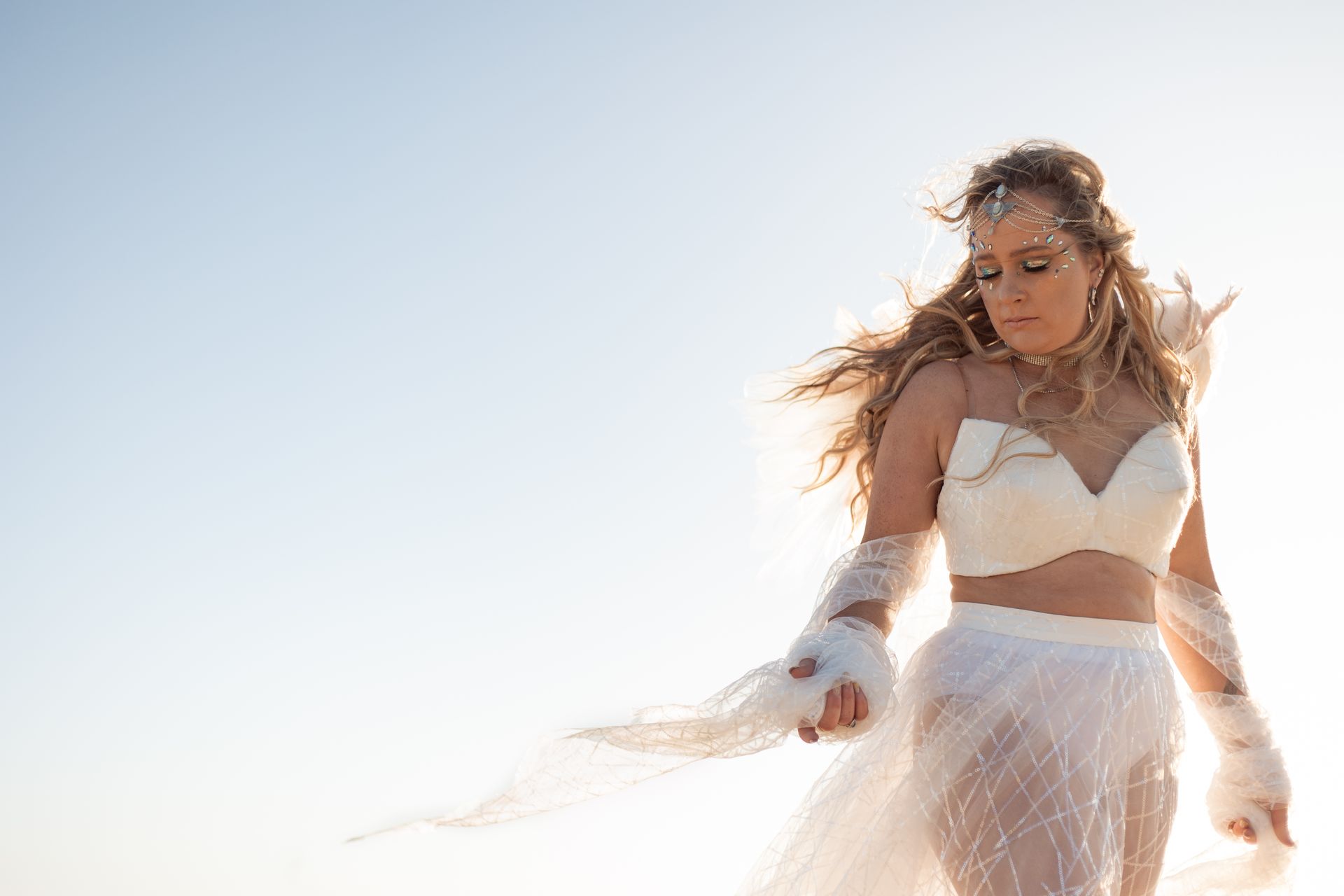 A woman in a white dress is standing in the desert.
