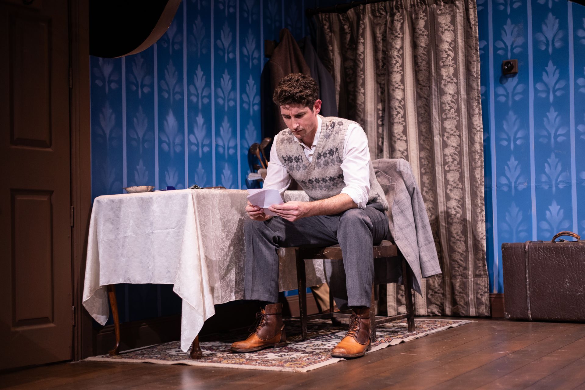 A man is sitting in a chair reading a letter.