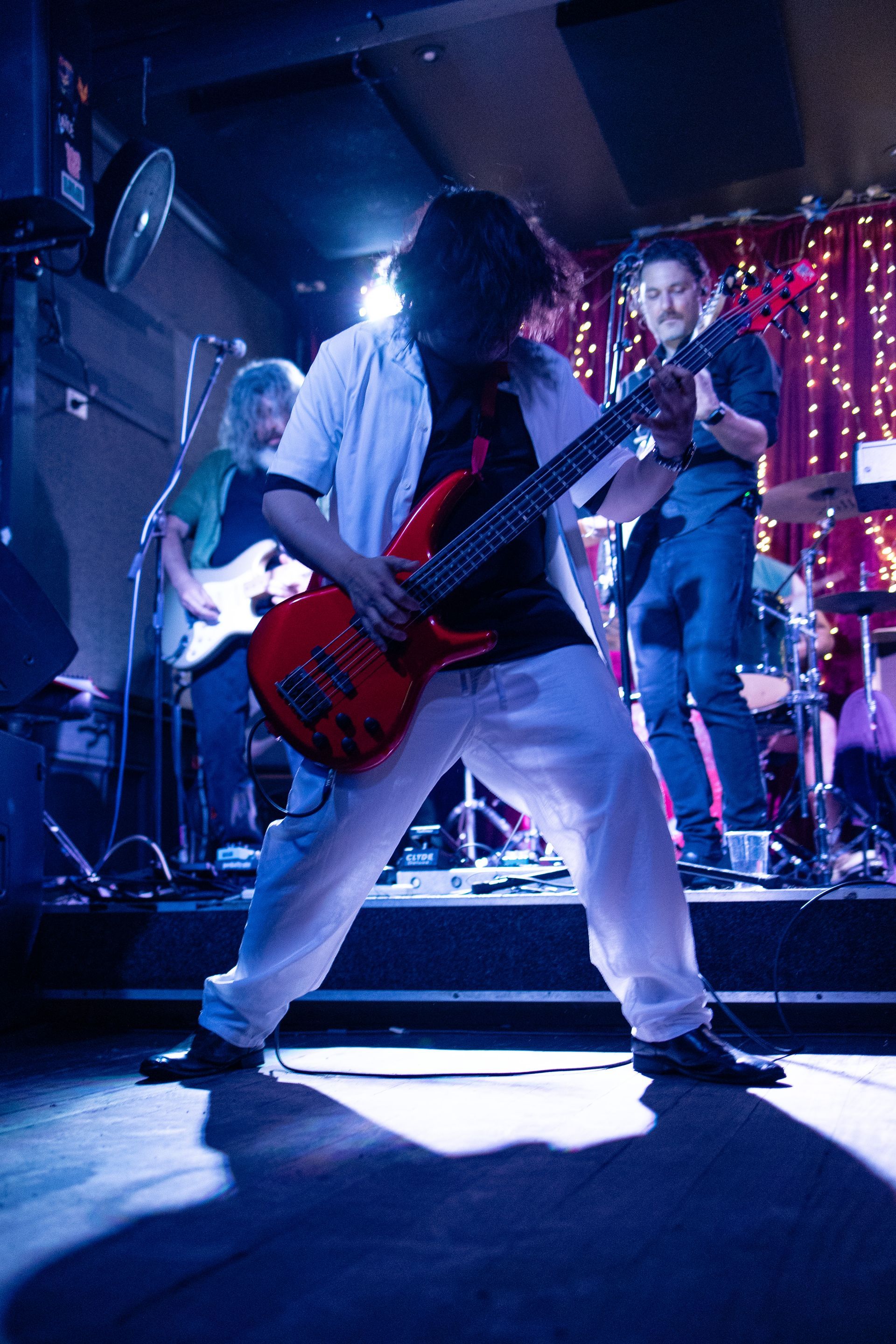 A man is playing a red guitar on stage in front of a band.