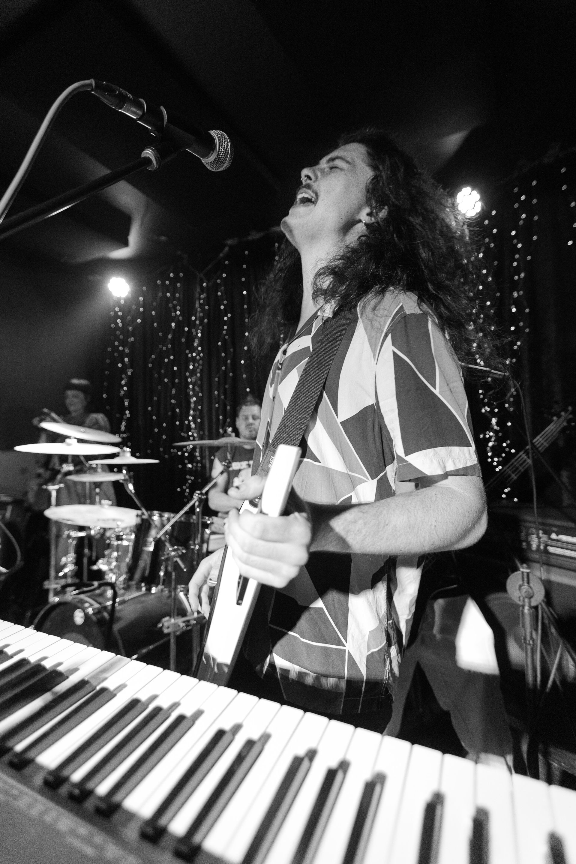 A man singing into a microphone while playing a keyboard