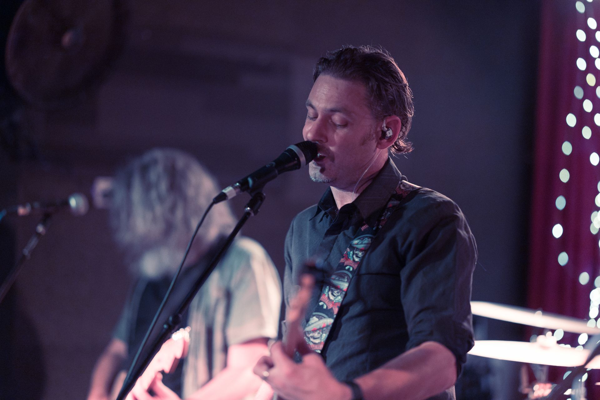 A man singing into a microphone while playing a guitar
