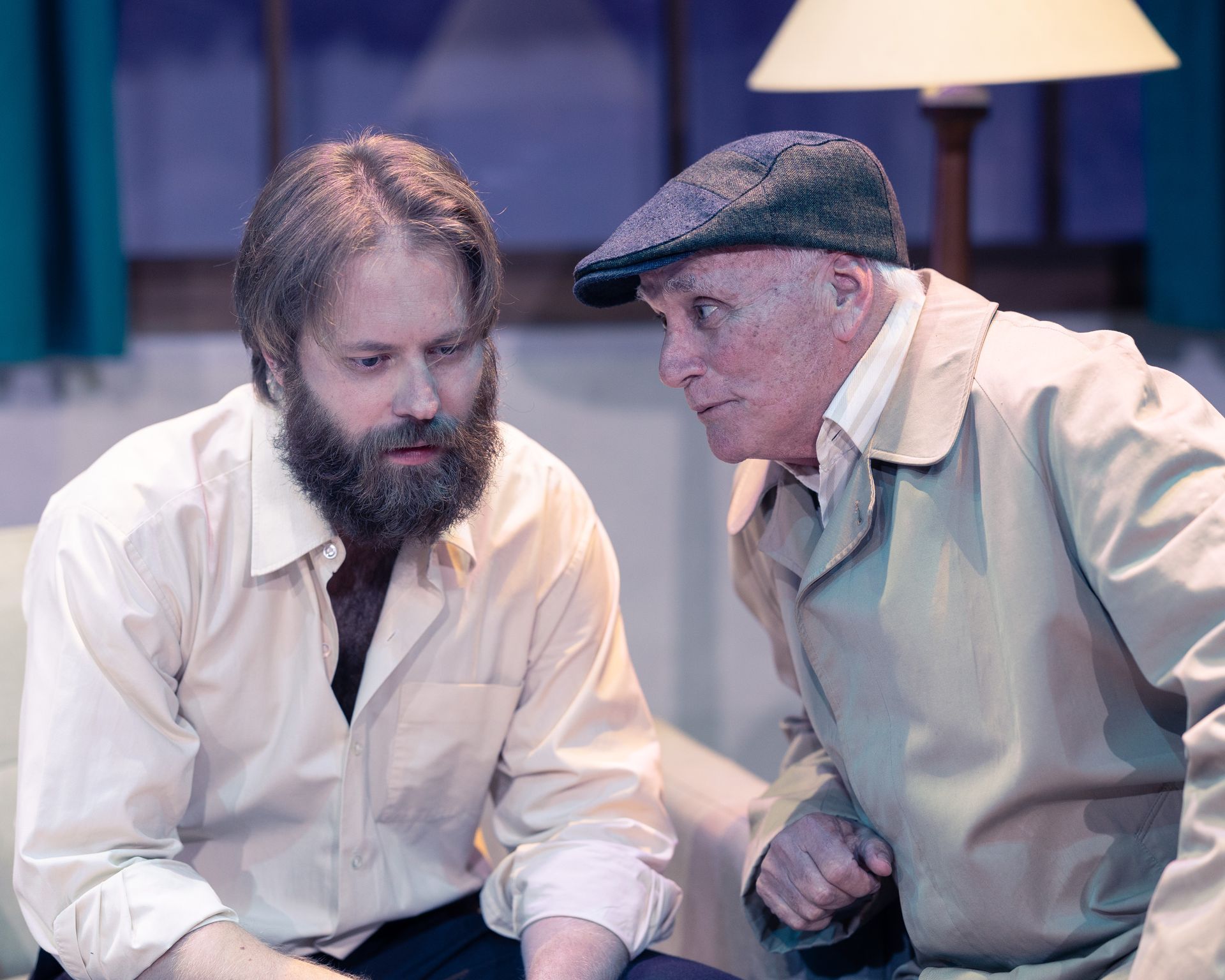 Two men are sitting on a couch and talking to each other