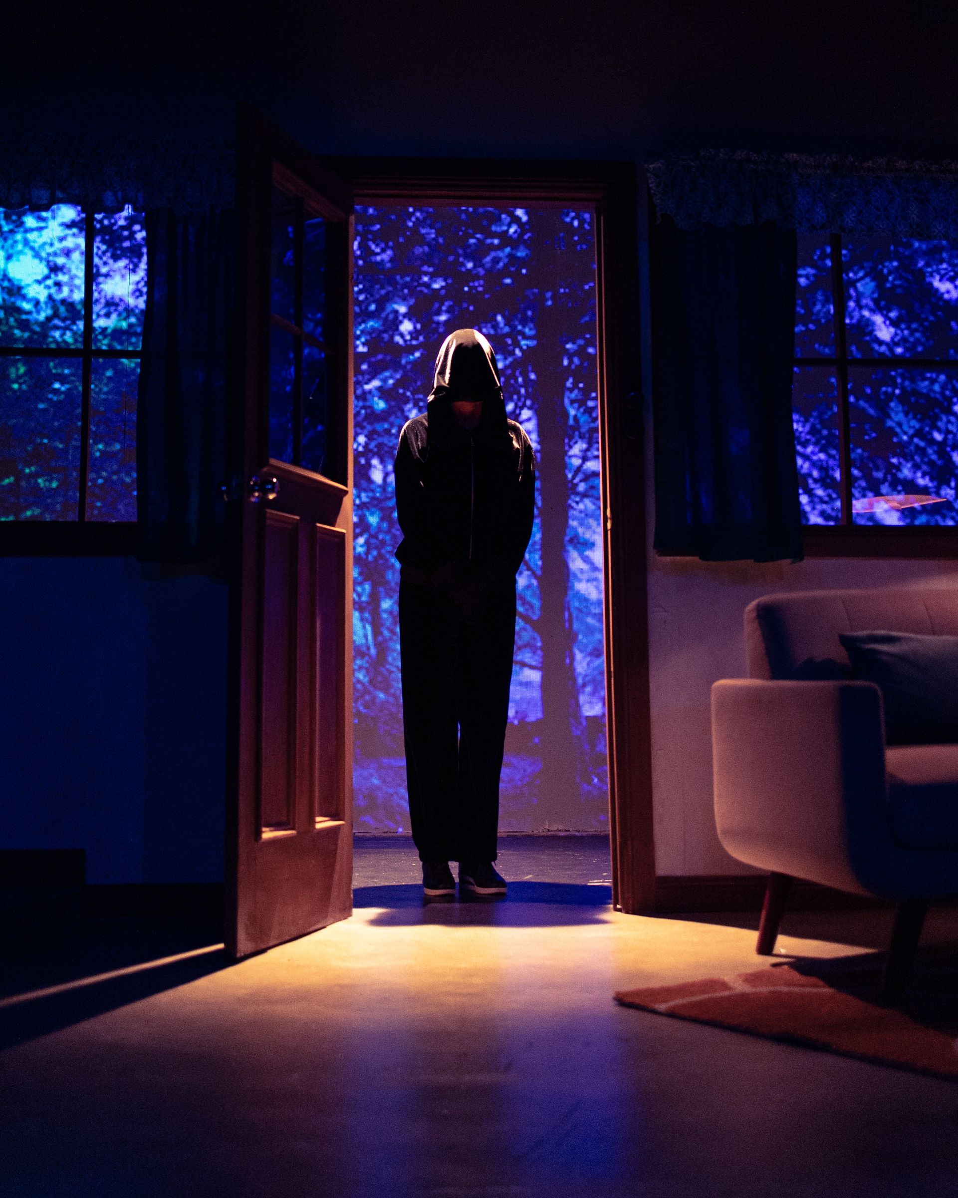 A man in a hooded jacket is standing in the doorway of a living room