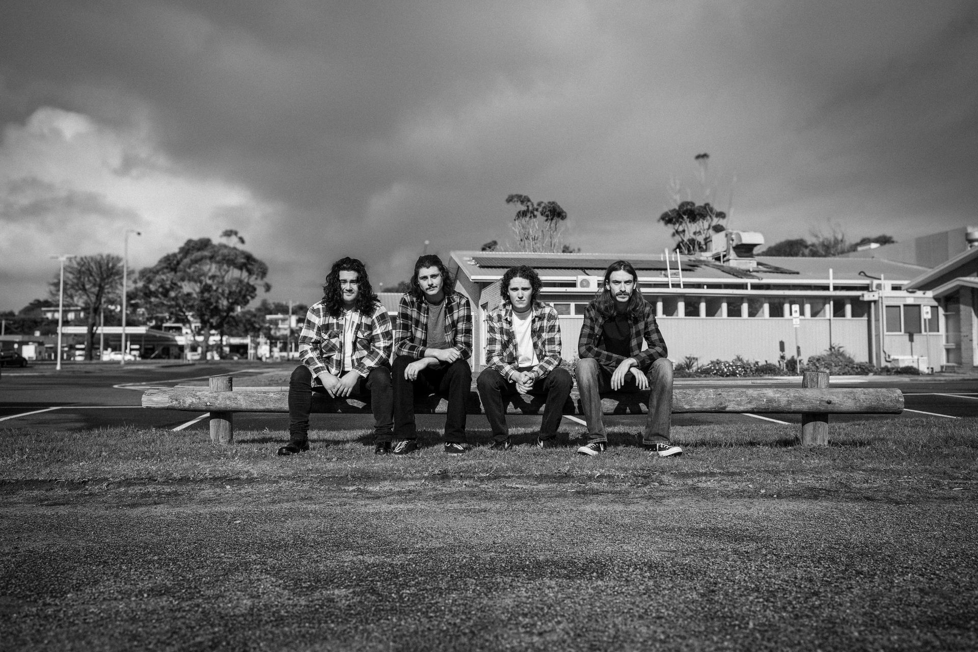 A group of men are sitting on a bench in front of a building.