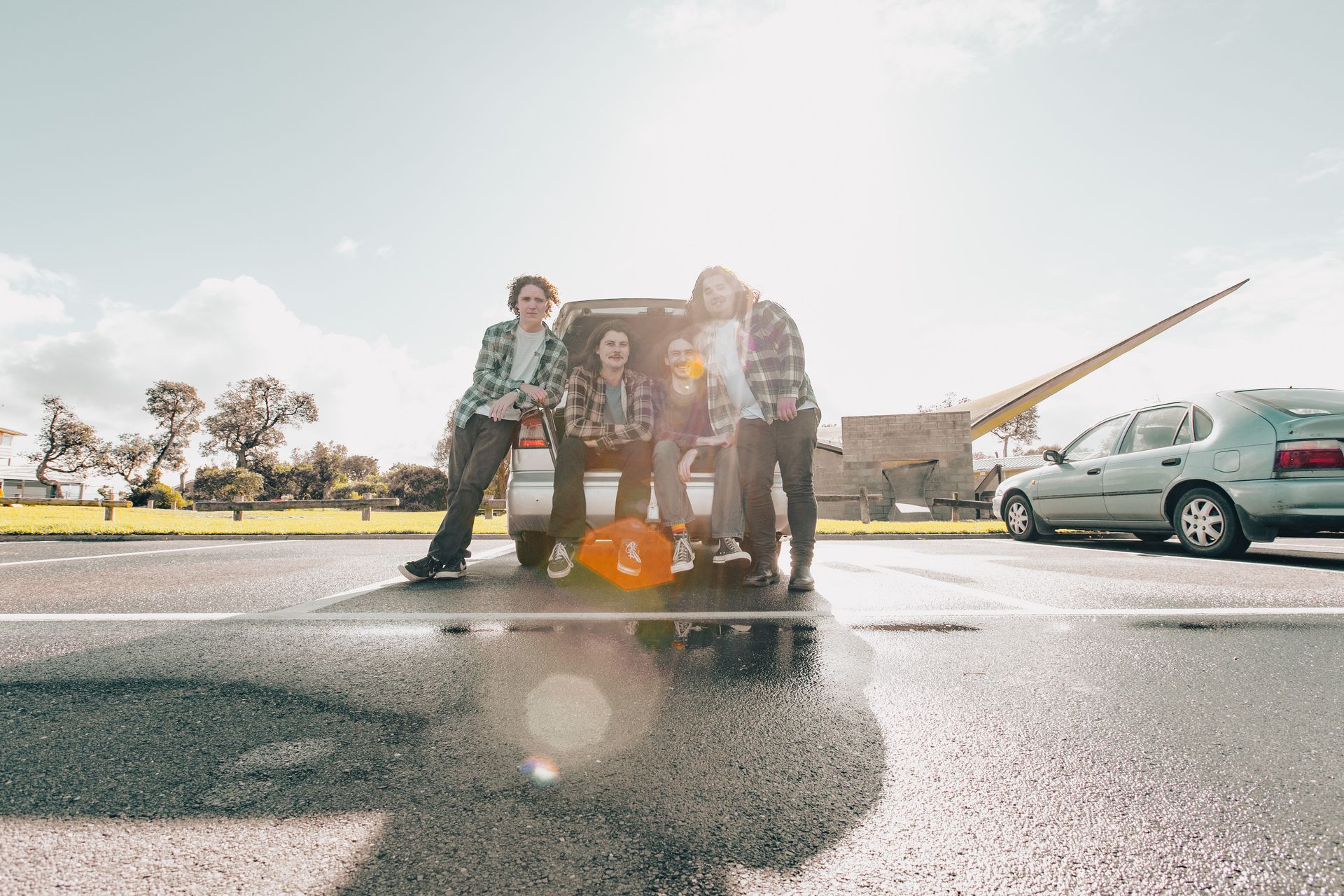 A group of people are standing in front of a van in a parking lot.