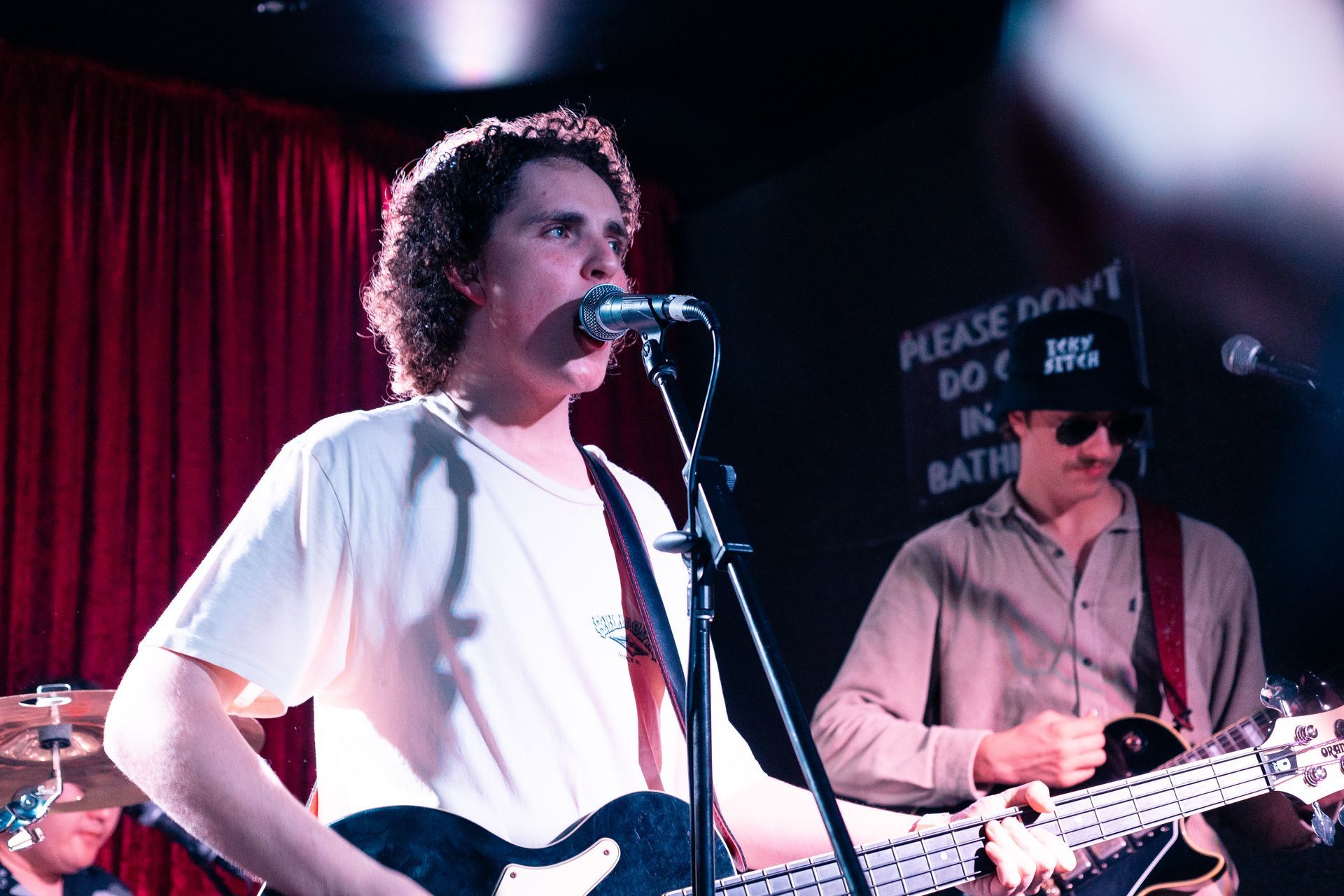 A man is singing into a microphone while playing a guitar.