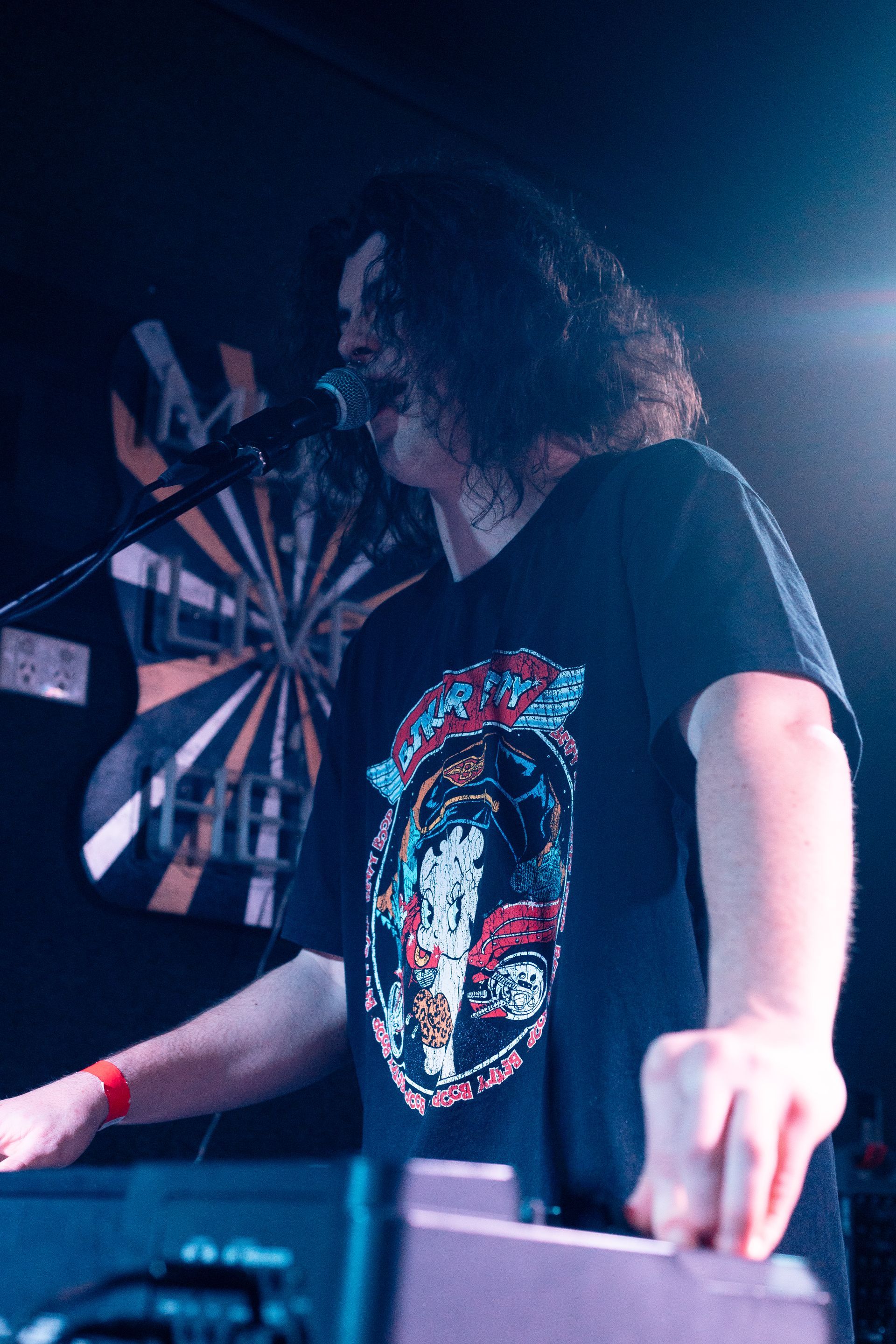 A man is singing into a microphone on a stage in front of a dart board.