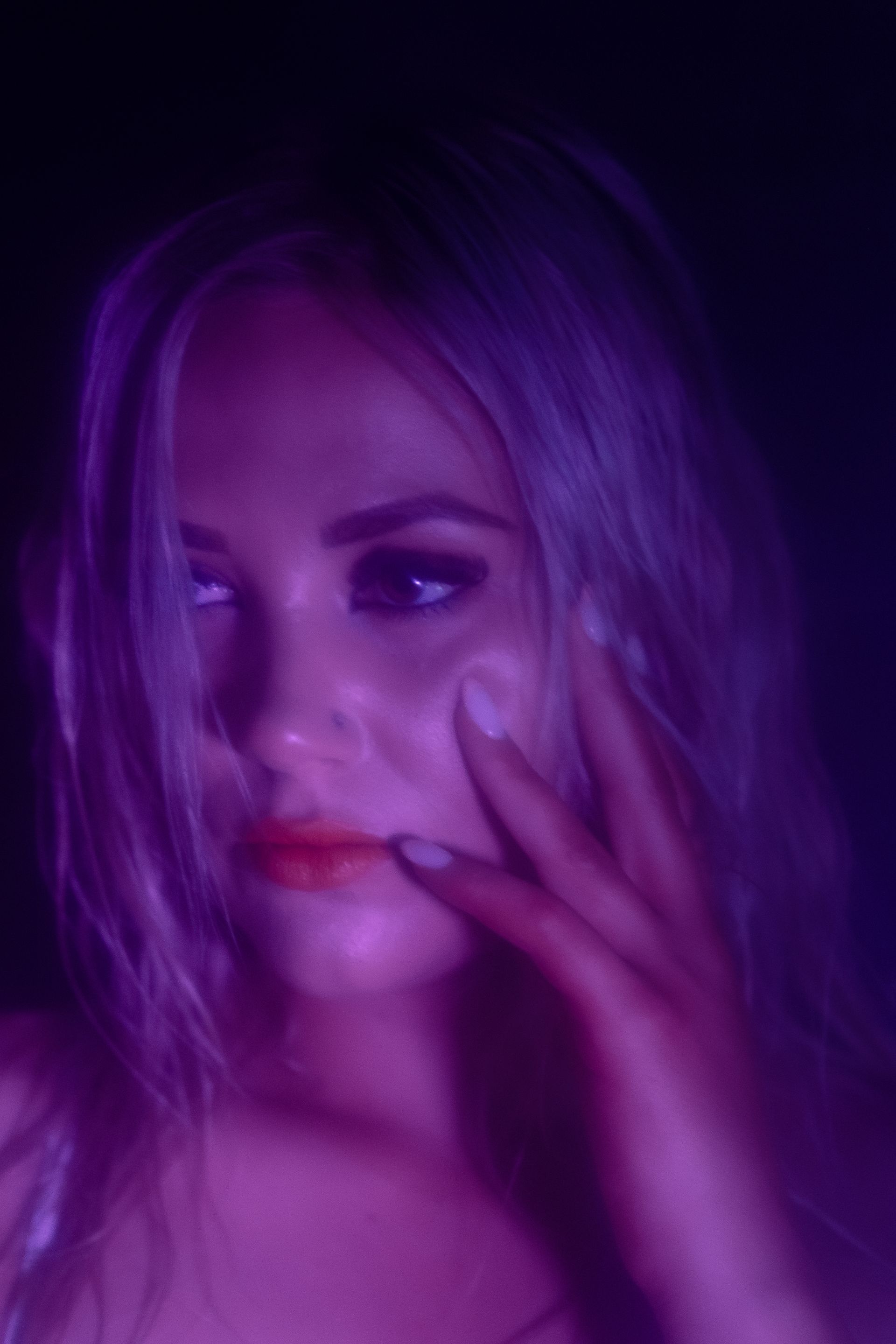 A close up of a woman 's face with purple lights behind her.