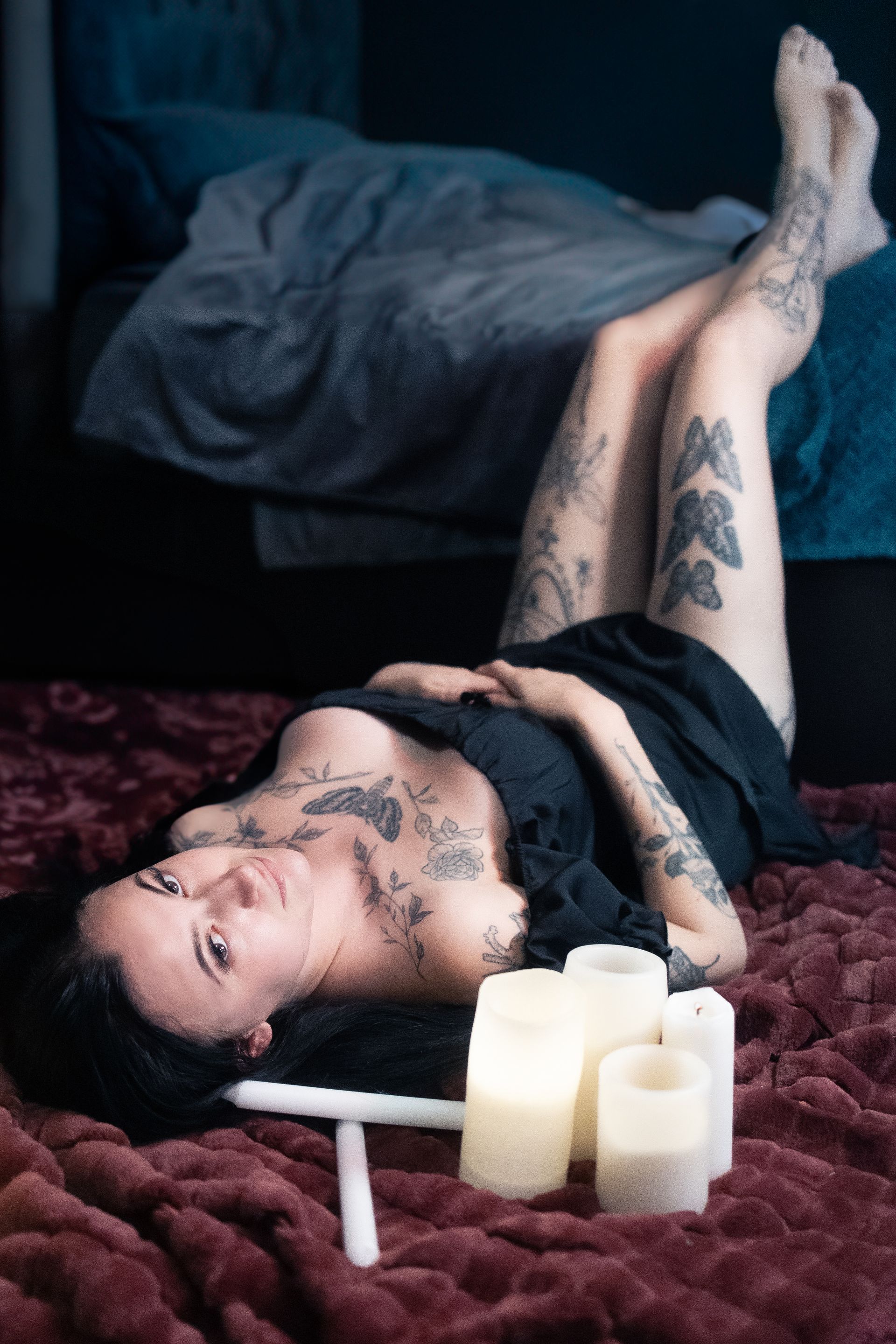 A woman is laying on her stomach on a bed next to candles.