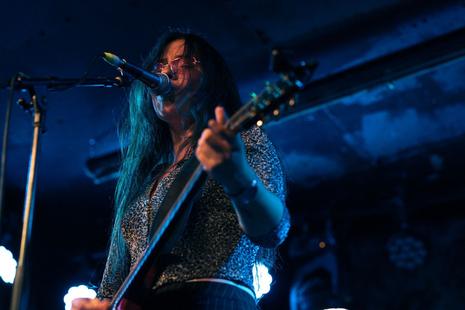 A woman is singing into a microphone while playing a guitar.