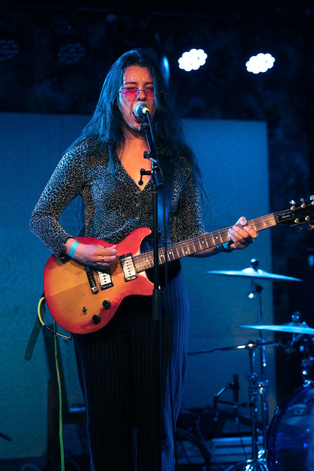 A woman is singing into a microphone while playing a guitar on stage.