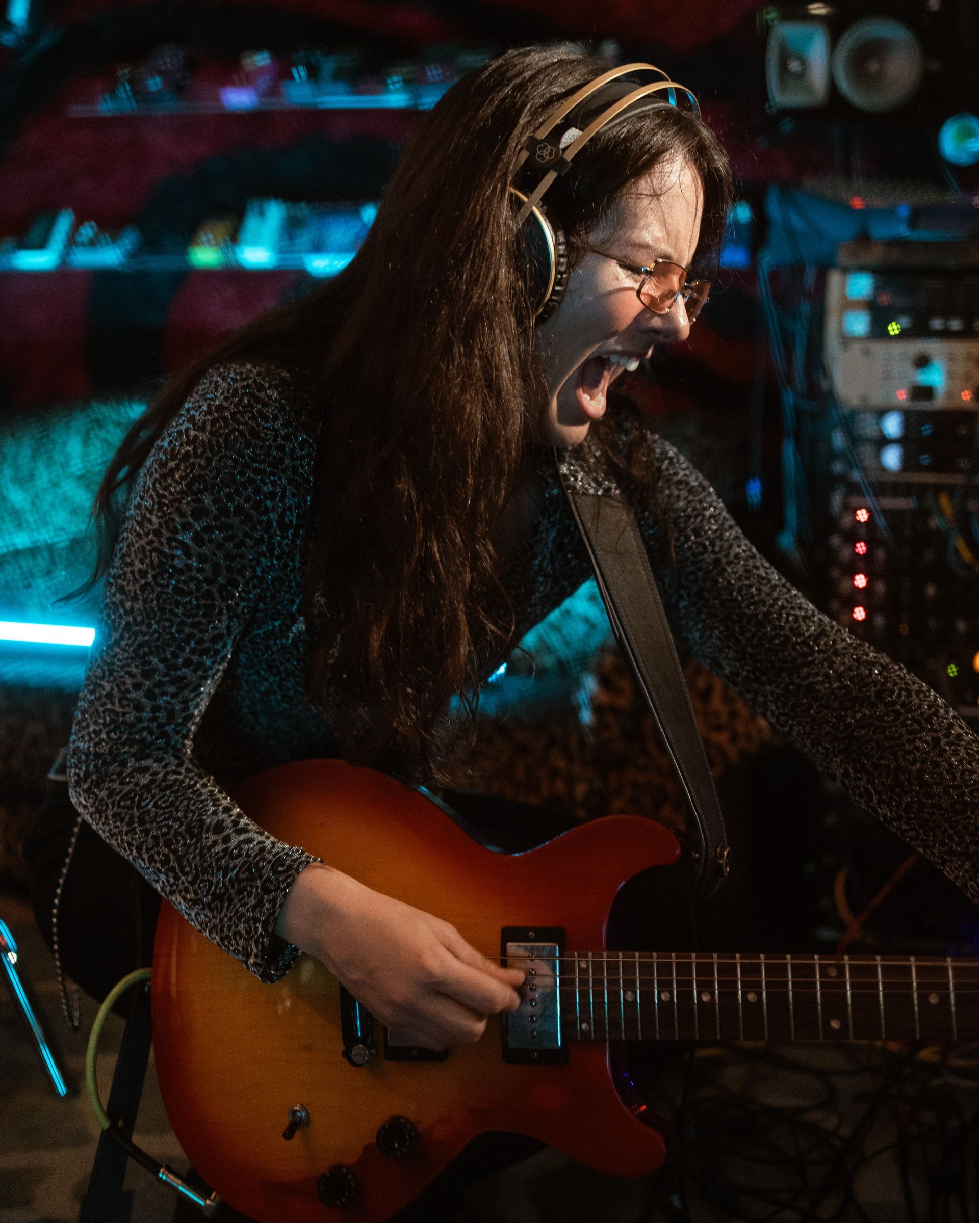 A woman wearing headphones is playing a guitar