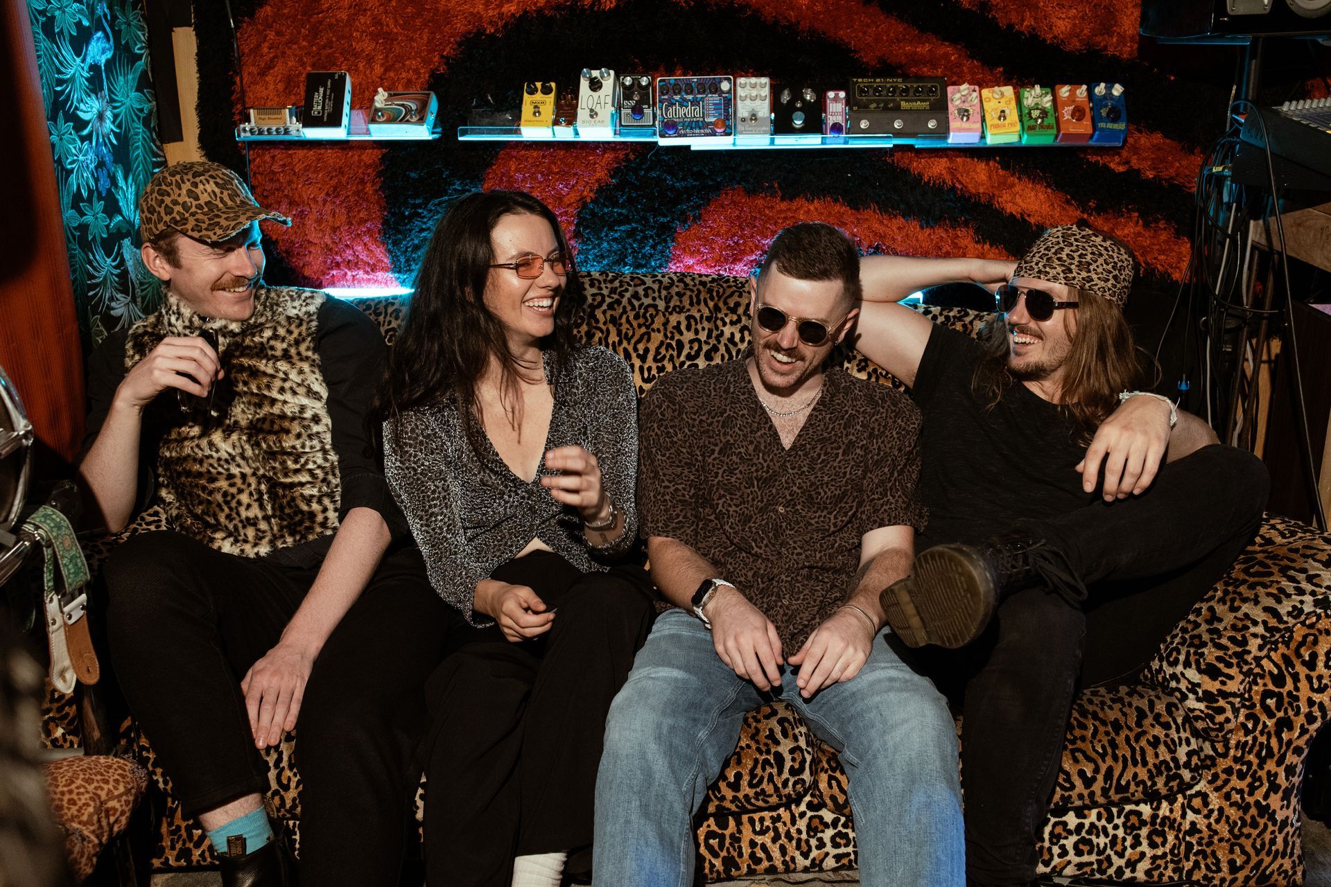 A group of people are sitting on a leopard print couch.