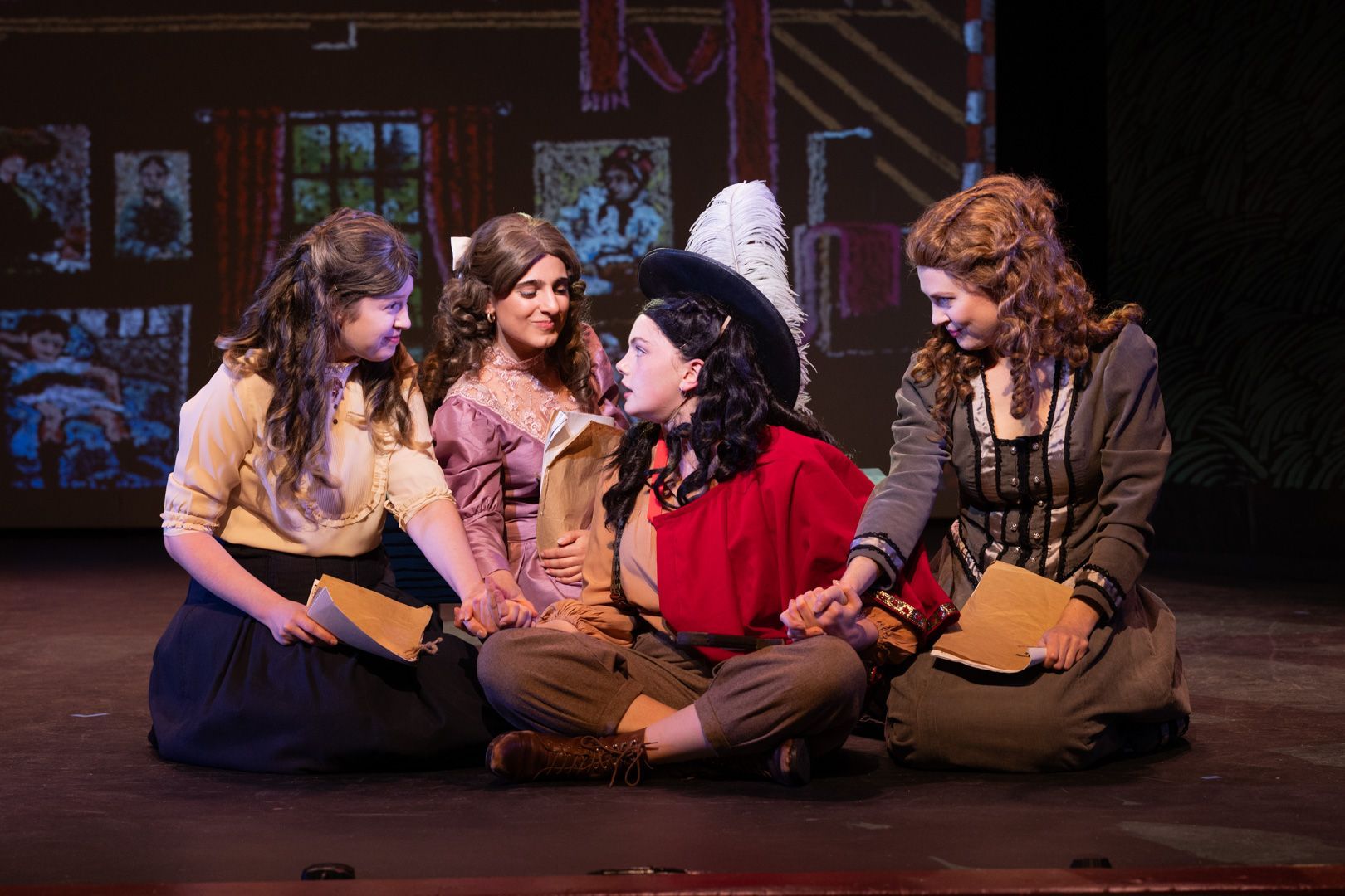 A group of women are sitting on the floor on a stage.