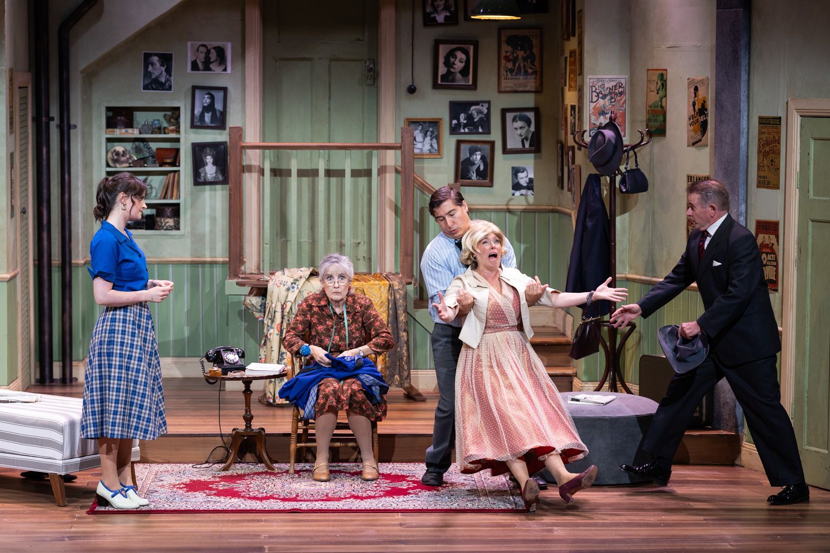 A group of people are dancing on a stage in a living room.
