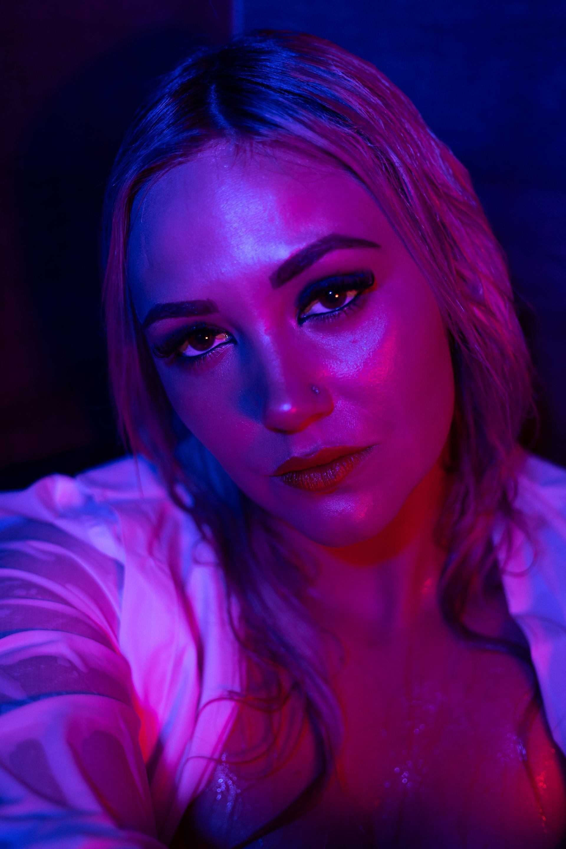 A close up of a woman 's face in purple and blue lights.