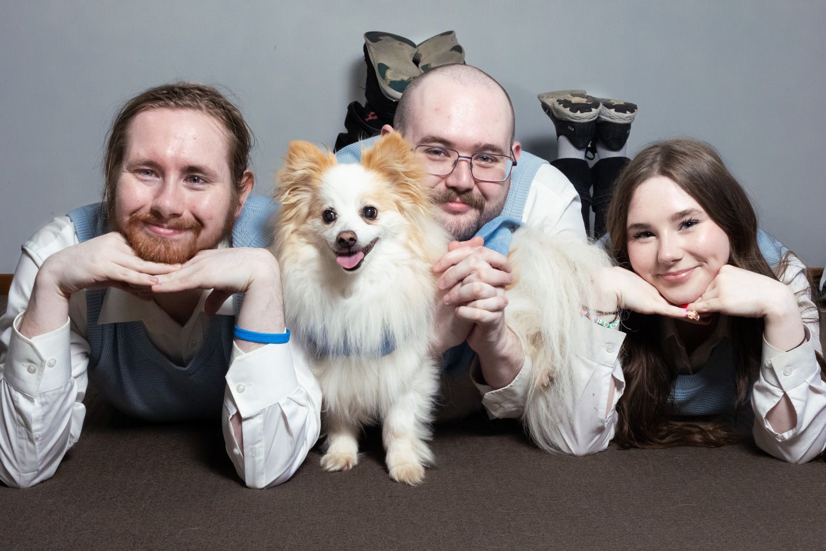 Two men and a woman are posing for a picture with their dog