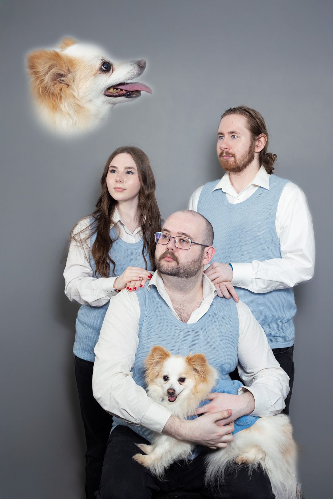 A family is posing for a picture with their dog.