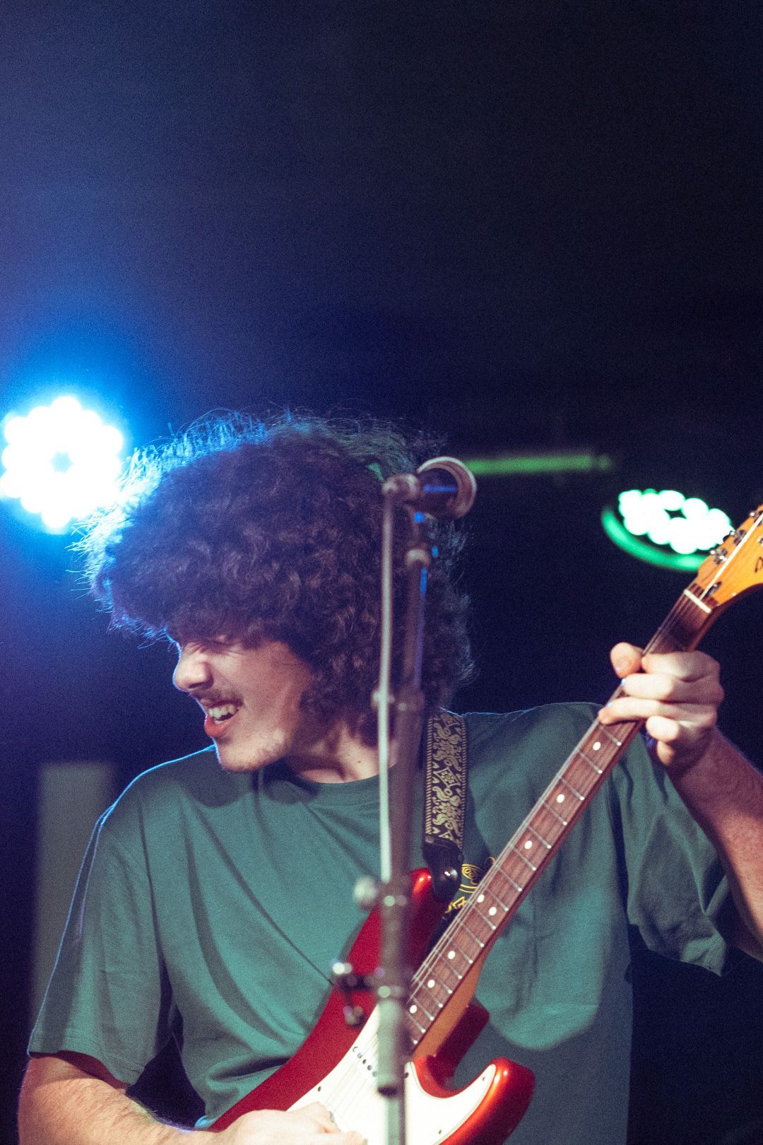 A man in a green shirt is playing a guitar and singing into a microphone