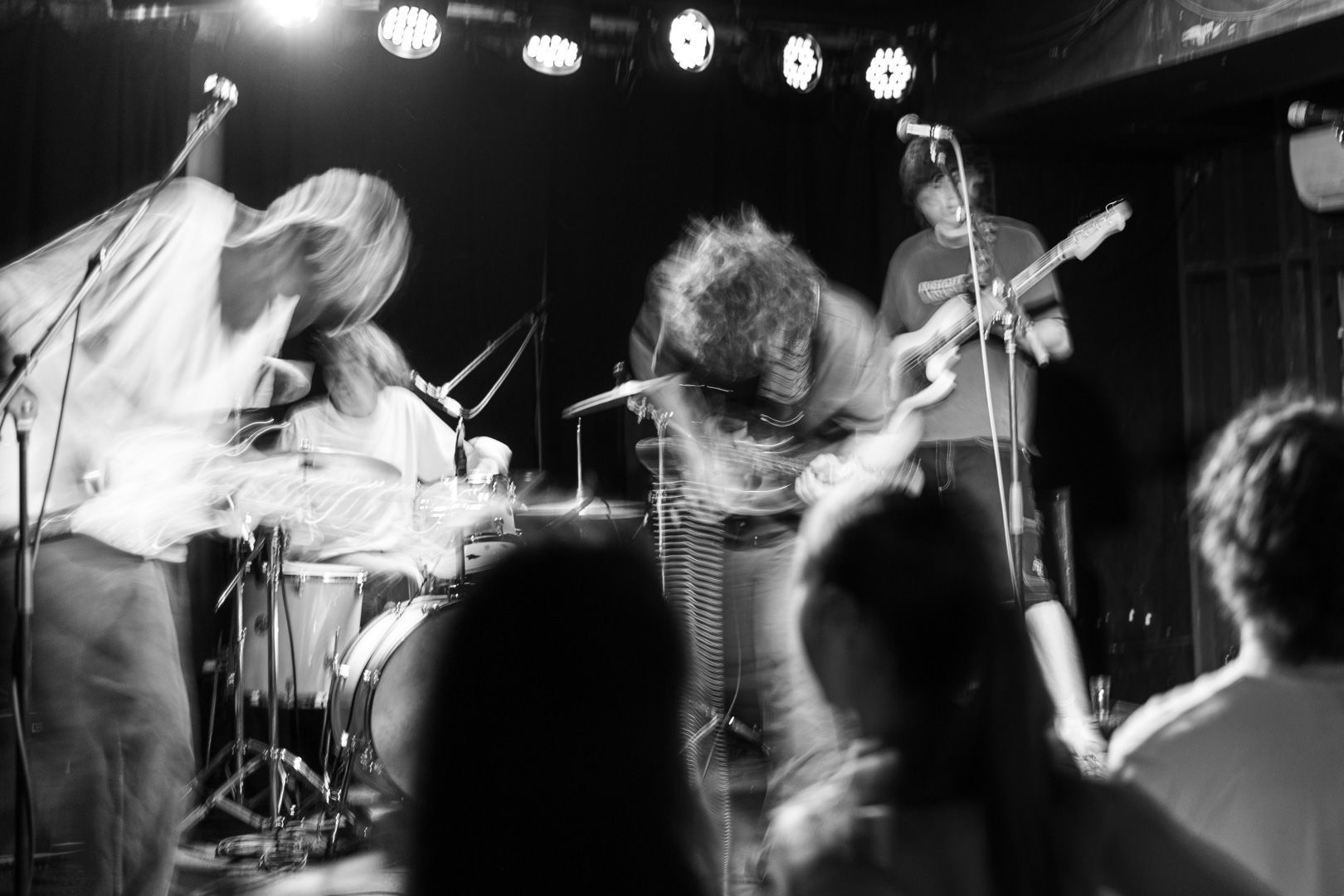 A black and white photo of a group of people playing instruments on a stage.