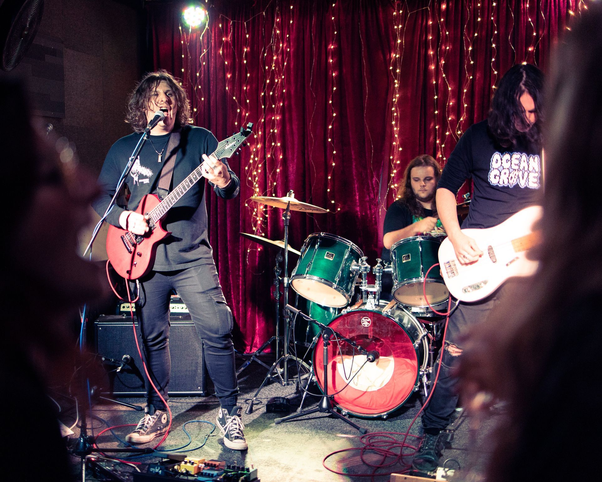 A man is singing into a microphone while playing a guitar on stage.