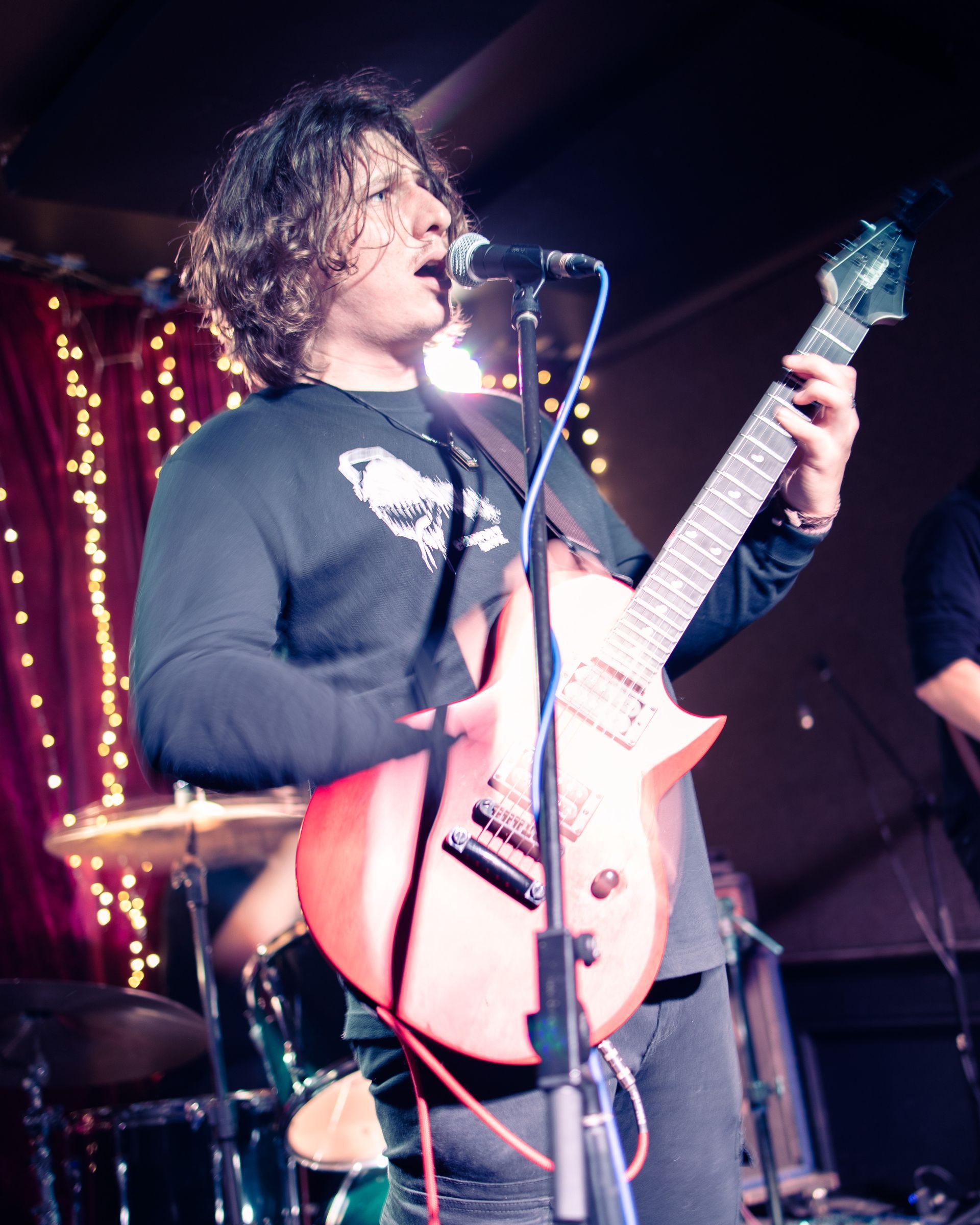A man singing into a microphone while playing a guitar