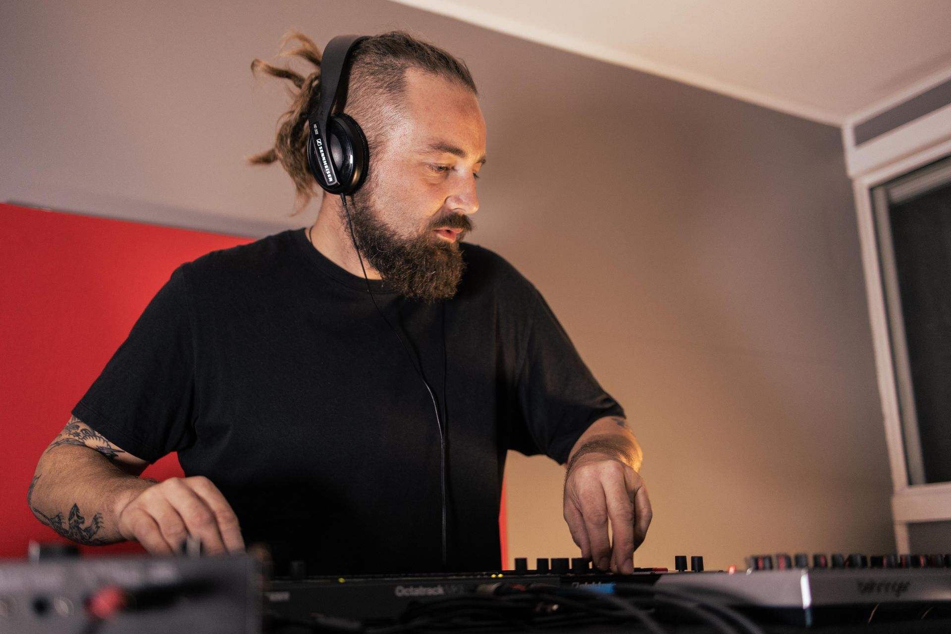 A man with a beard and headphones is playing music on a dj controller.