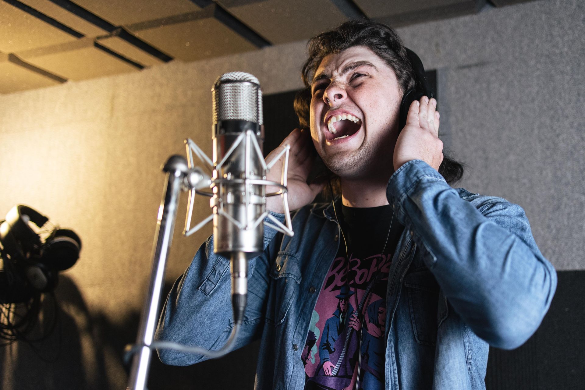 A man is singing into a microphone in a recording studio.