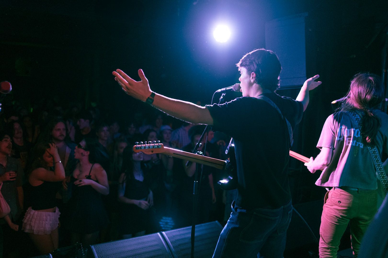A man is playing a guitar on stage in front of a crowd.