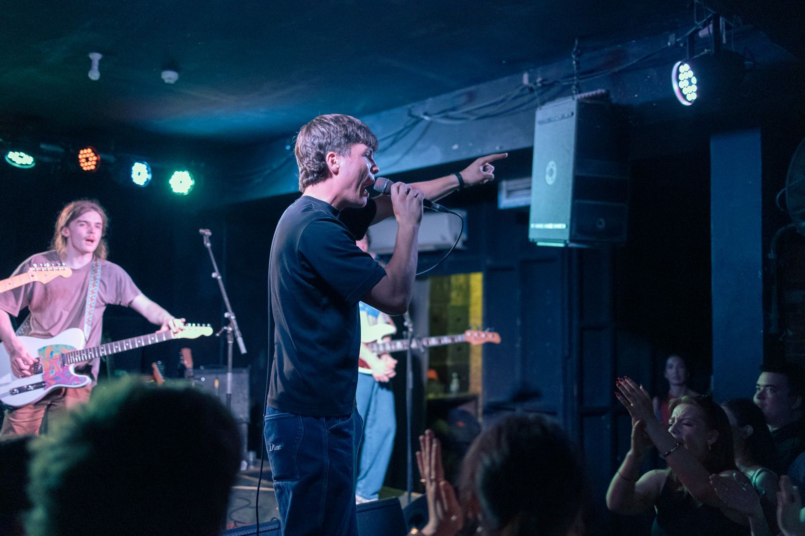 A man is singing into a microphone on a stage in front of a crowd.