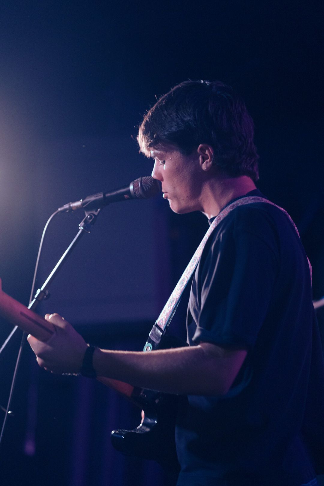 A man is singing into a microphone while playing a guitar.