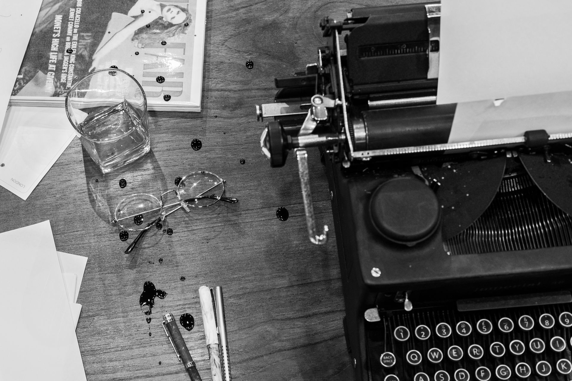 A black and white photo of a typewriter and a glass of water