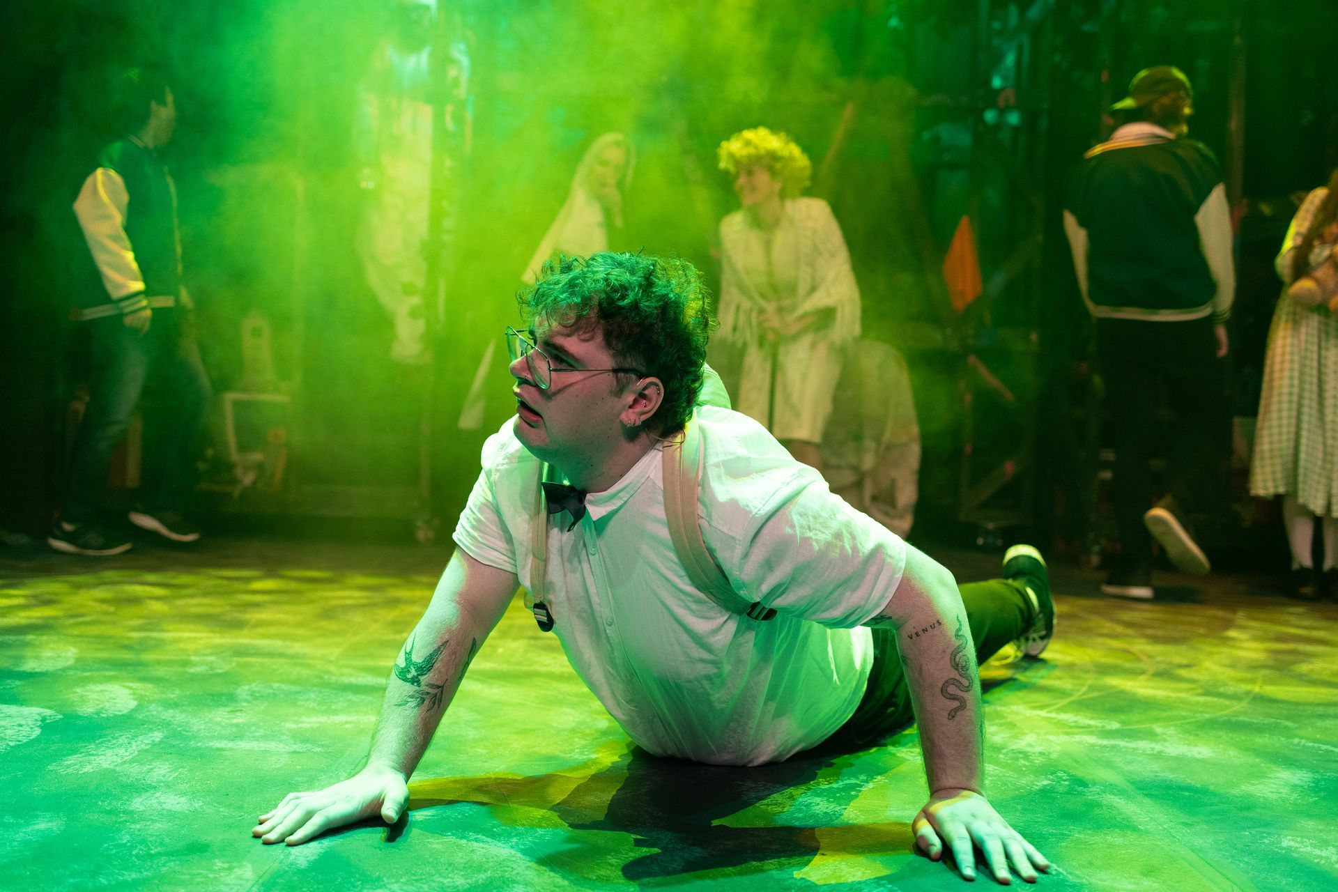 A man is crawling on the floor on a stage.