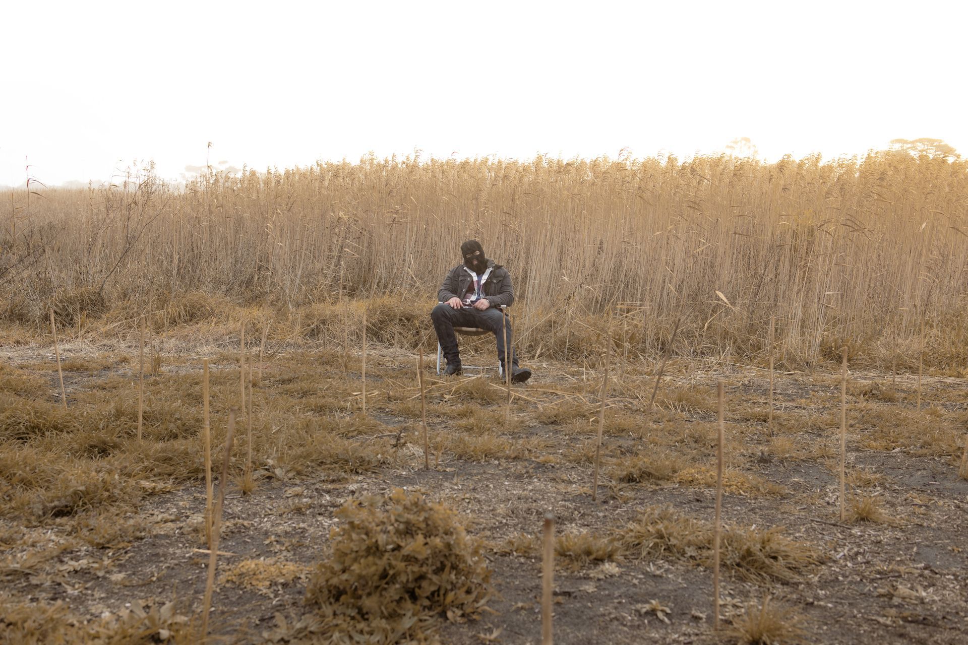 A man is sitting in a chair in the middle of a field.