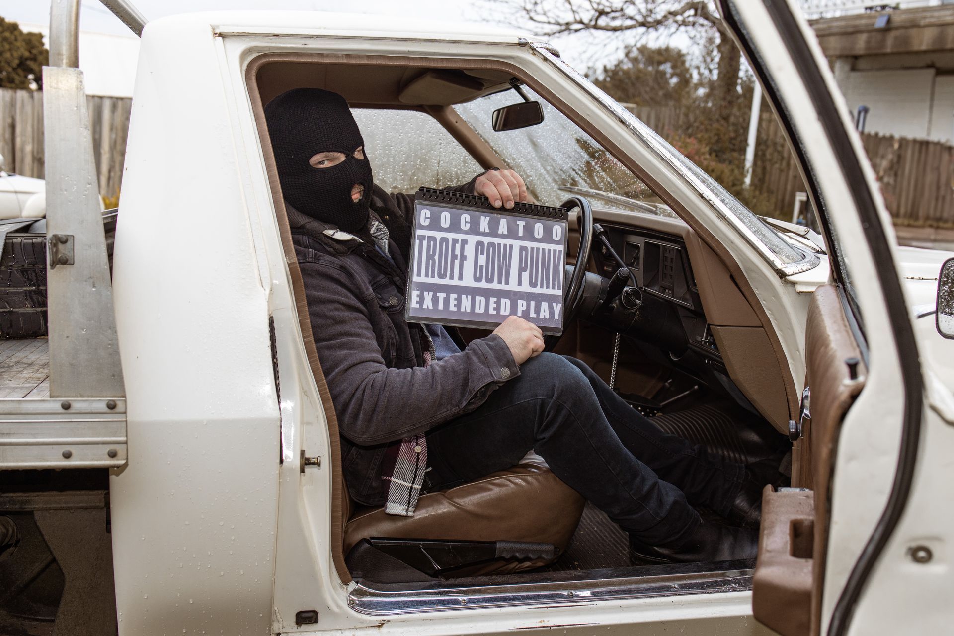 A man in a mask is sitting in the driver 's seat of a truck holding a sign.
