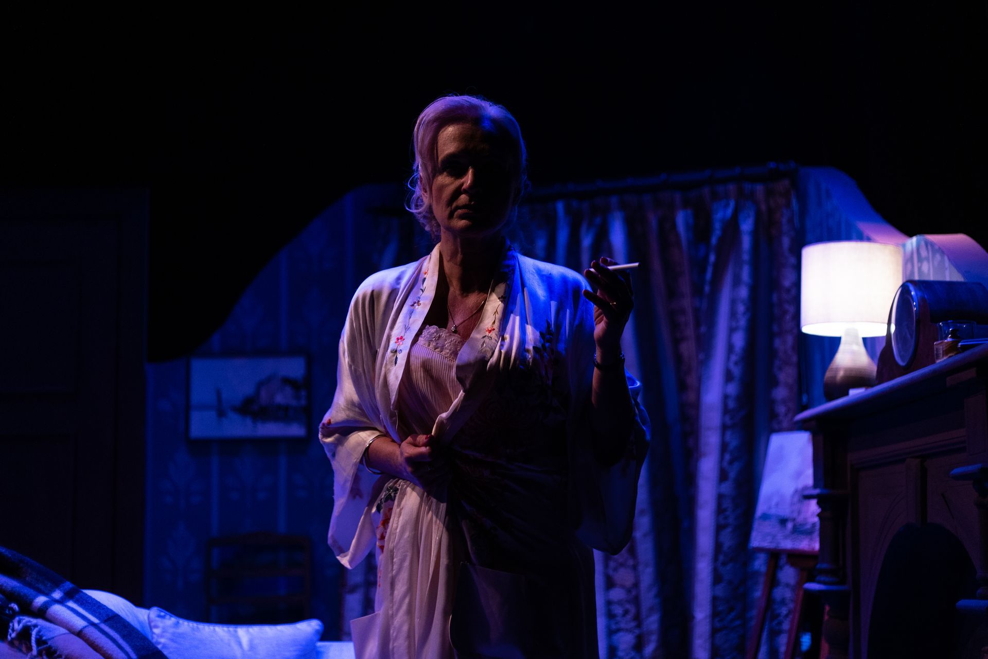 A woman in a robe is standing on a stage in a dark room.