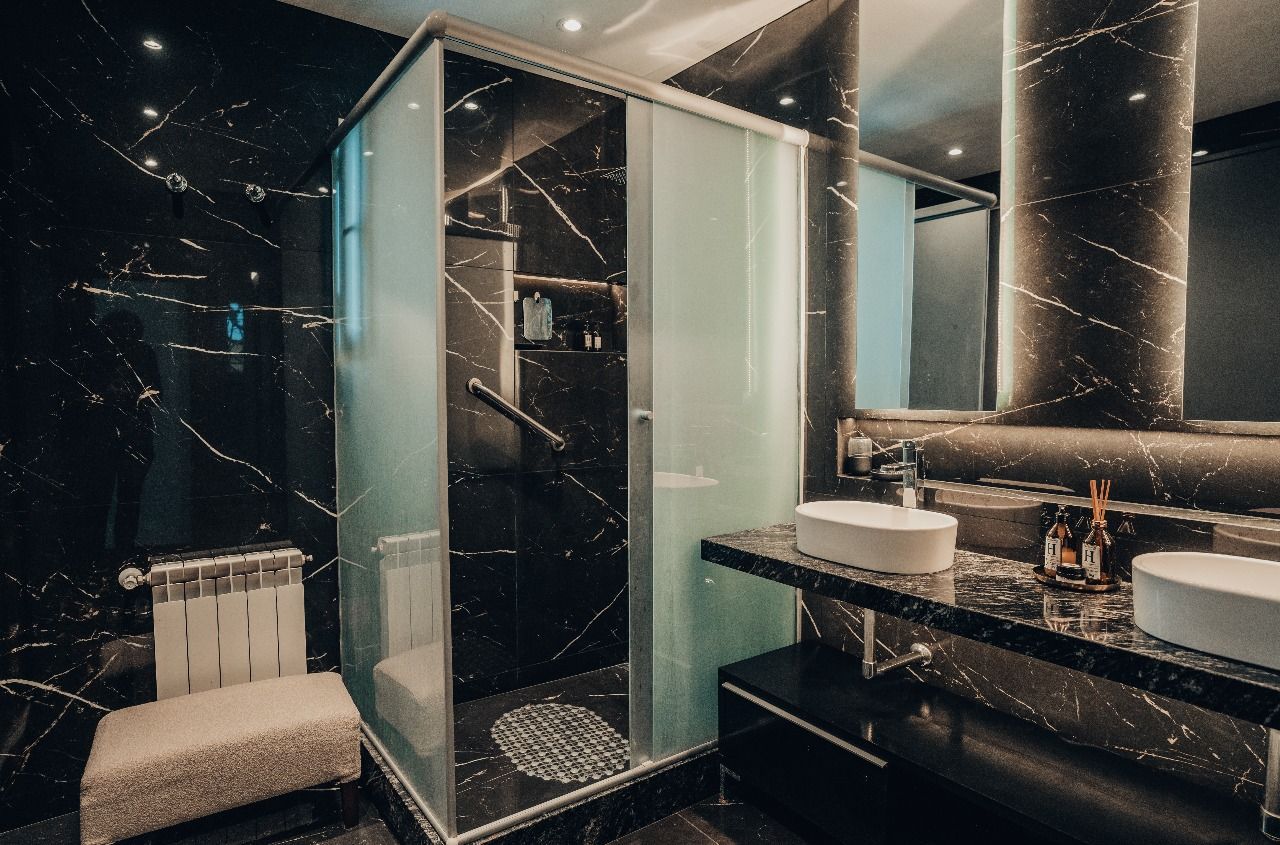 Un baño con ducha a ras de suelo y dos lavabos.