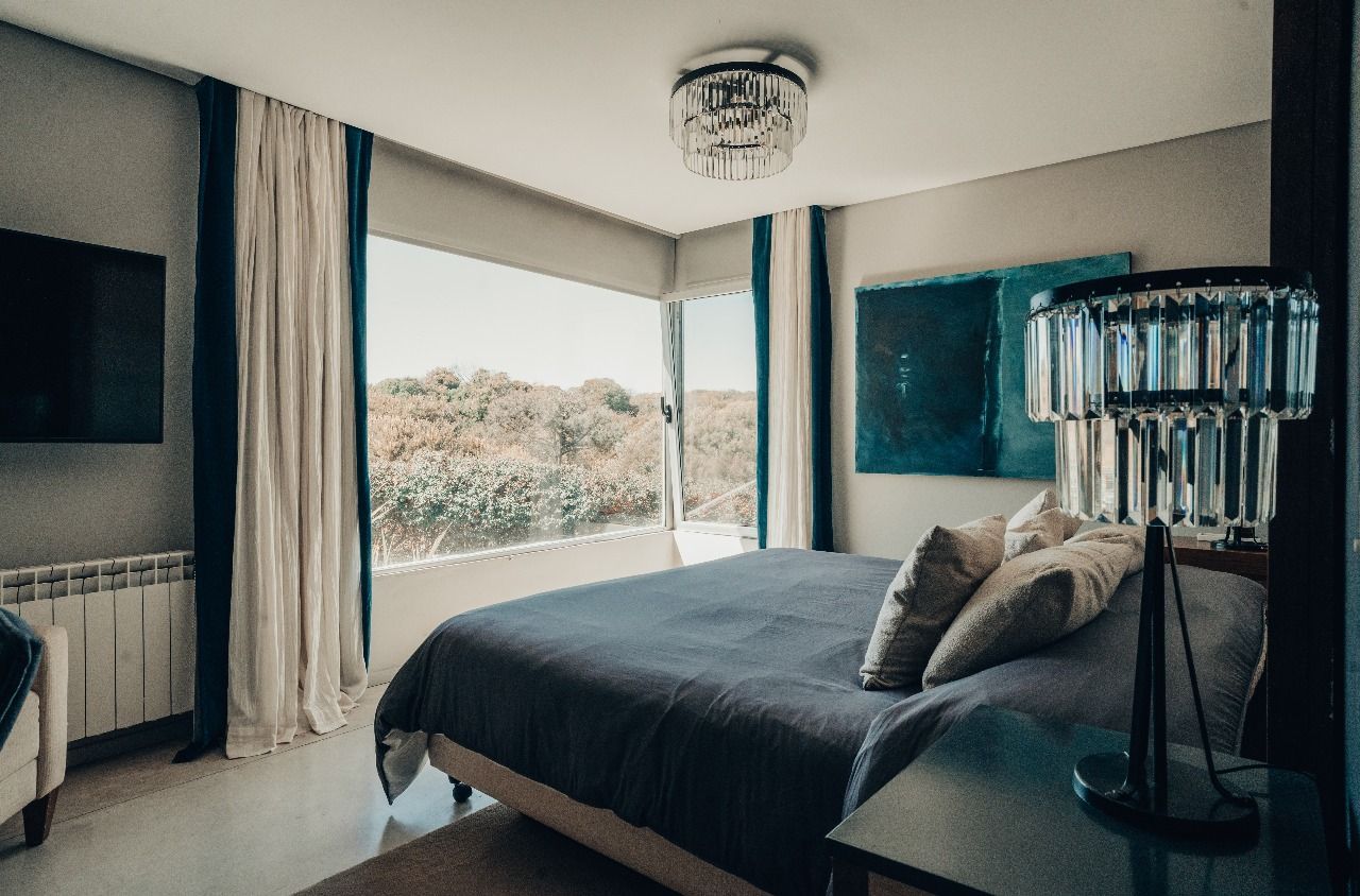 Un dormitorio con una cama king size, un televisor, una lámpara y una gran ventana.