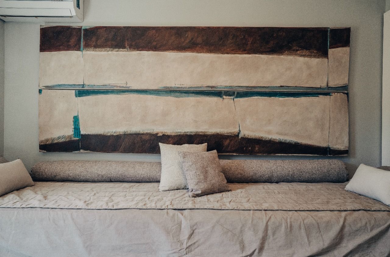 Un sofá con almohadas y un gran cuadro en la pared encima.
