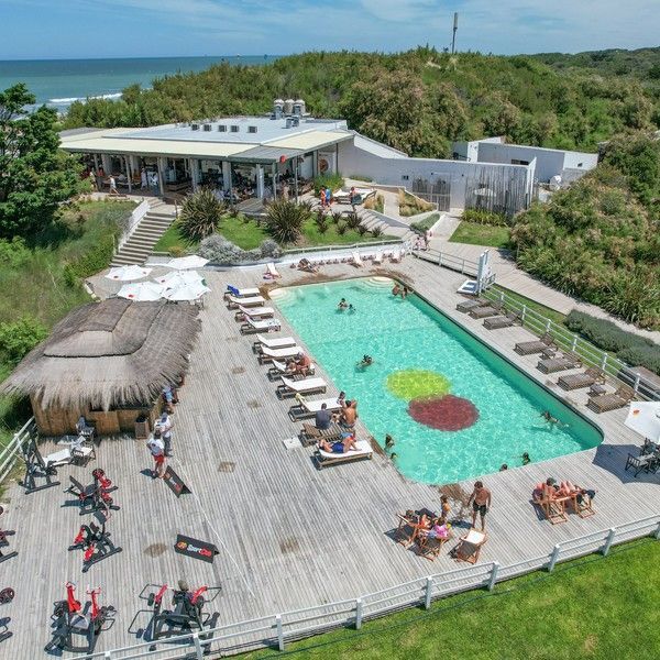 Una vista aérea de una gran piscina rodeada de sillas y sombrillas.