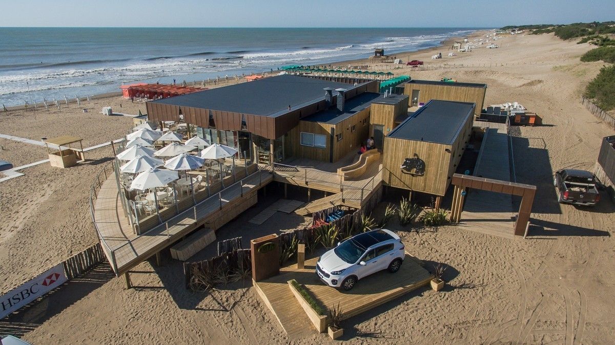 Una vista aérea de una playa con un coche aparcado delante de un edificio.
